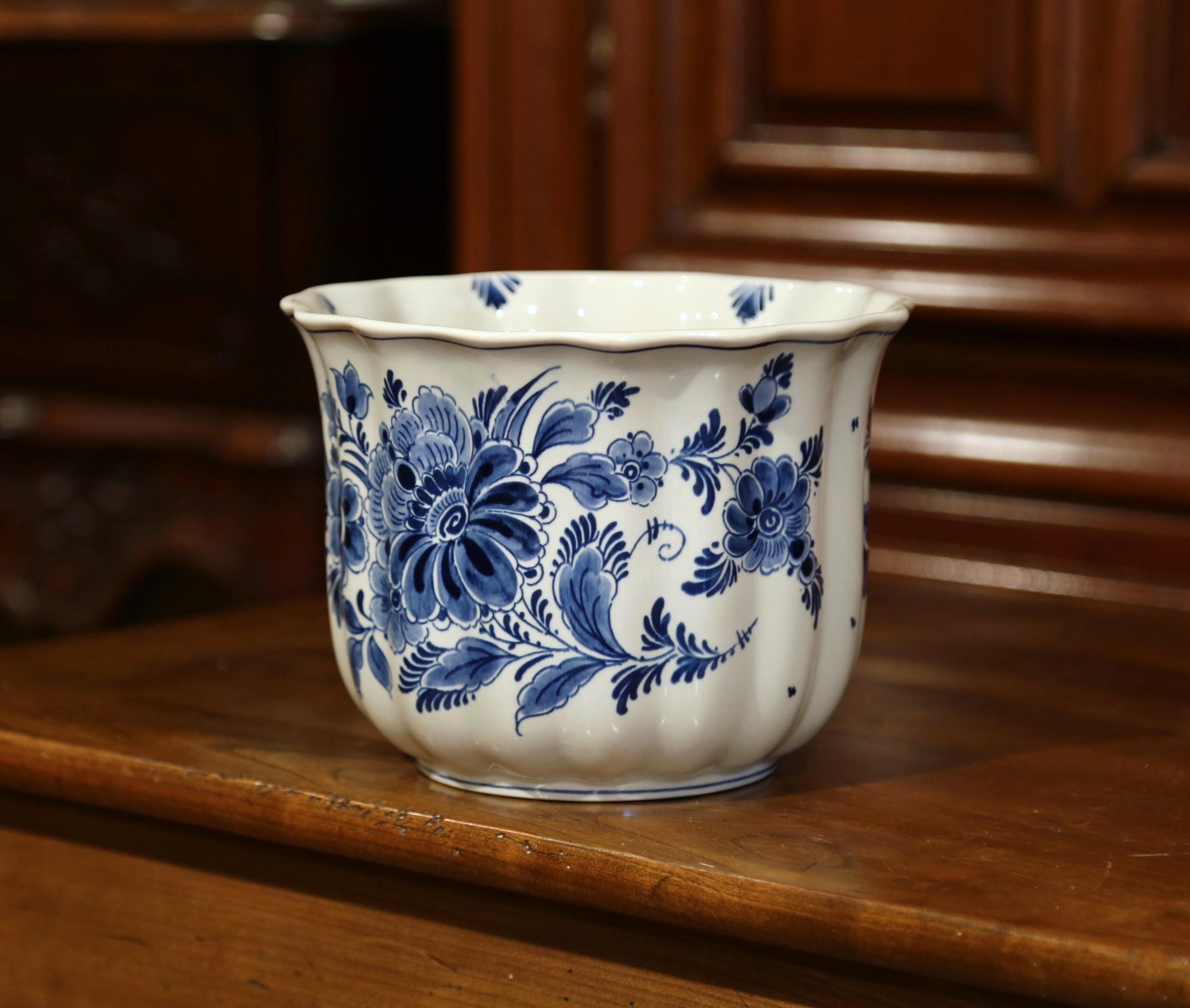 Handcrafted and hand-painted in Holland circa 1970, the round faience planter features floral decor in the traditional blue and white palette. The ceramic cache pot is signed on the bottom 