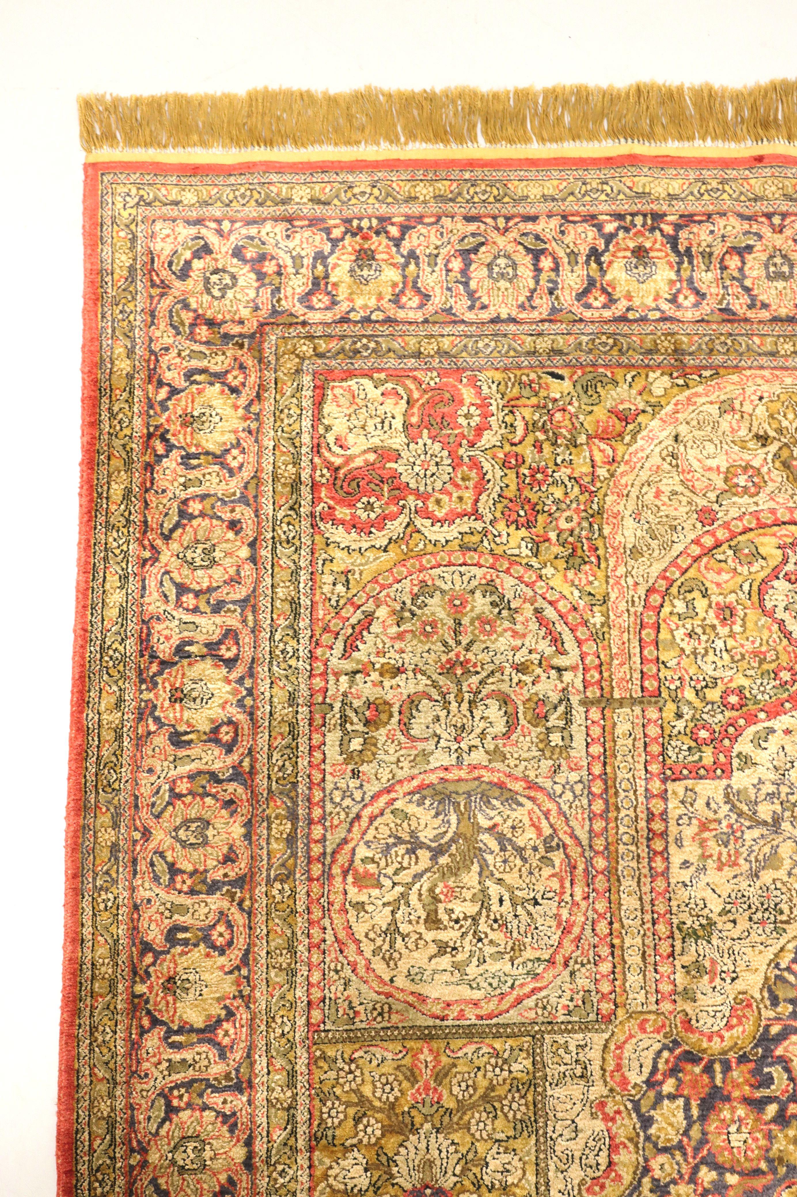 A Traditional Oriental style area rug, unbranded. Hand-knotted of high-quality silk and wool. Multi-color, primarily shades of red & gold, consisting of a distinctive design, and fringed ends. Origin unknown, likely Asia, from the late 20th