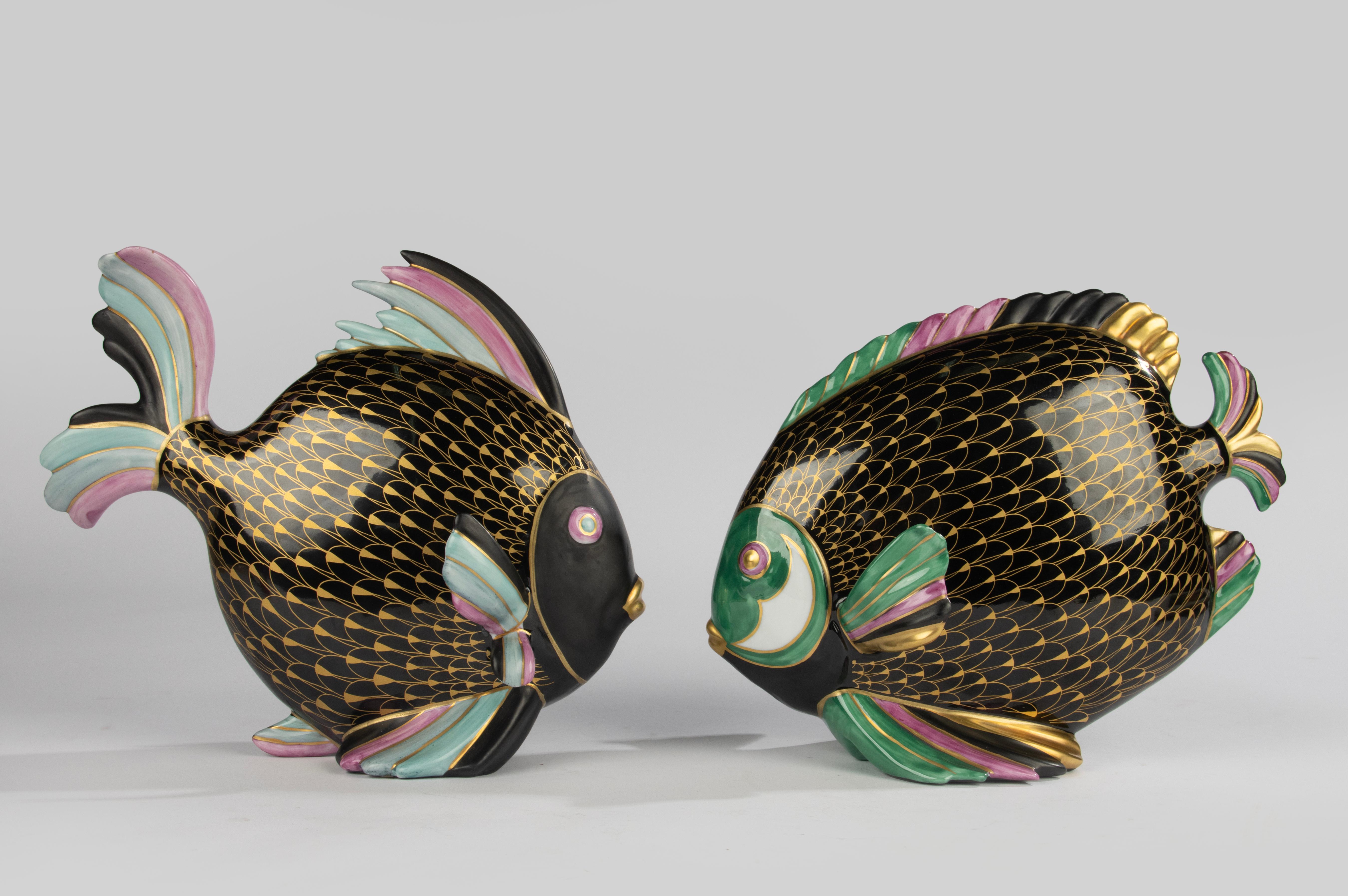 Eleganza della coppia di sculture di pesci in porcellana dipinta a mano della Manifattura Artistica Le Porcellane, Italia, risalenti alla fine del XX secolo. Ogni pezzo è splendidamente decorato con un fondo nero, riflessi pastello in rosa, verde e