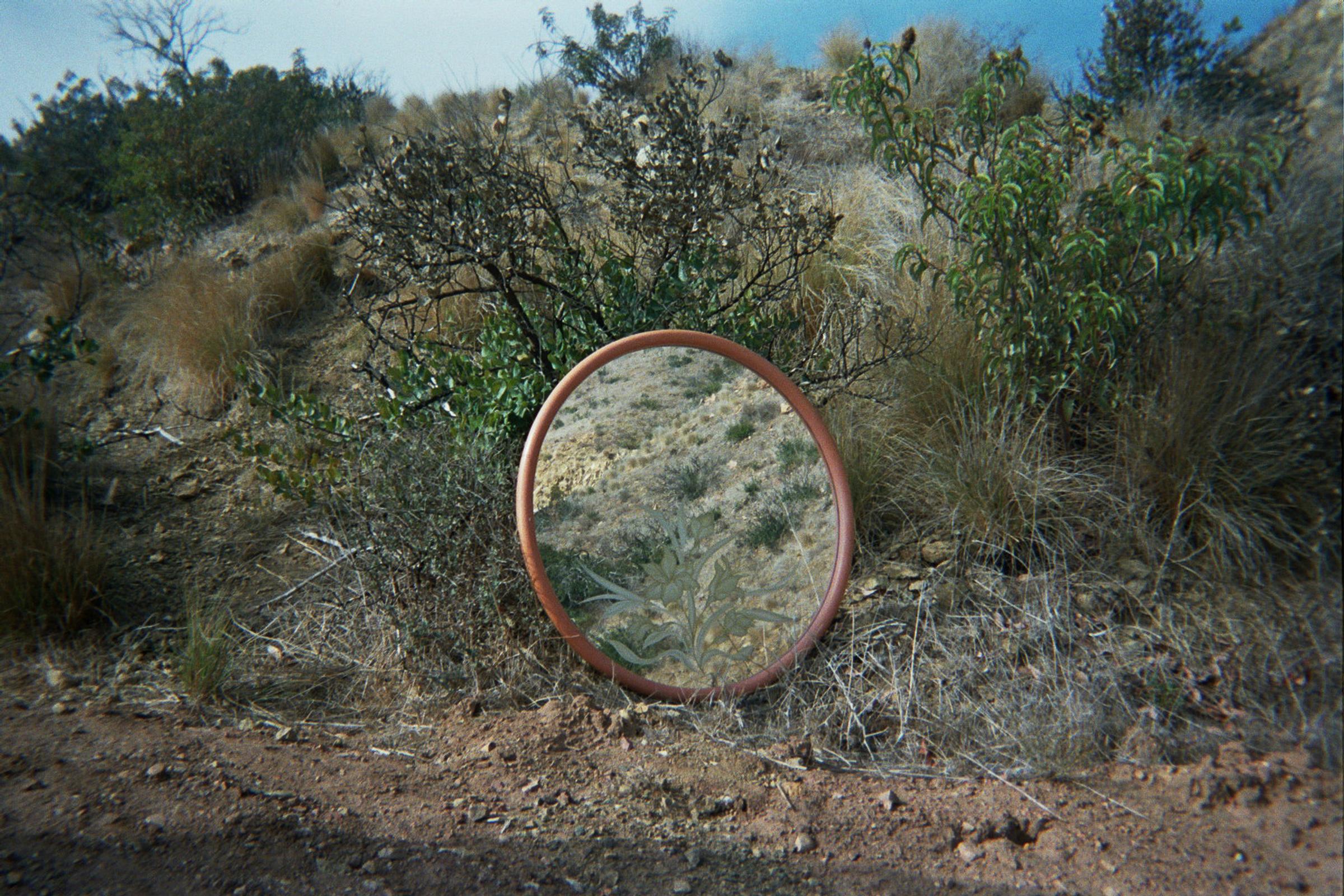 This large 1970-1980s round mirror features an etched floral pattern and a pink/salmon colors wood frame.