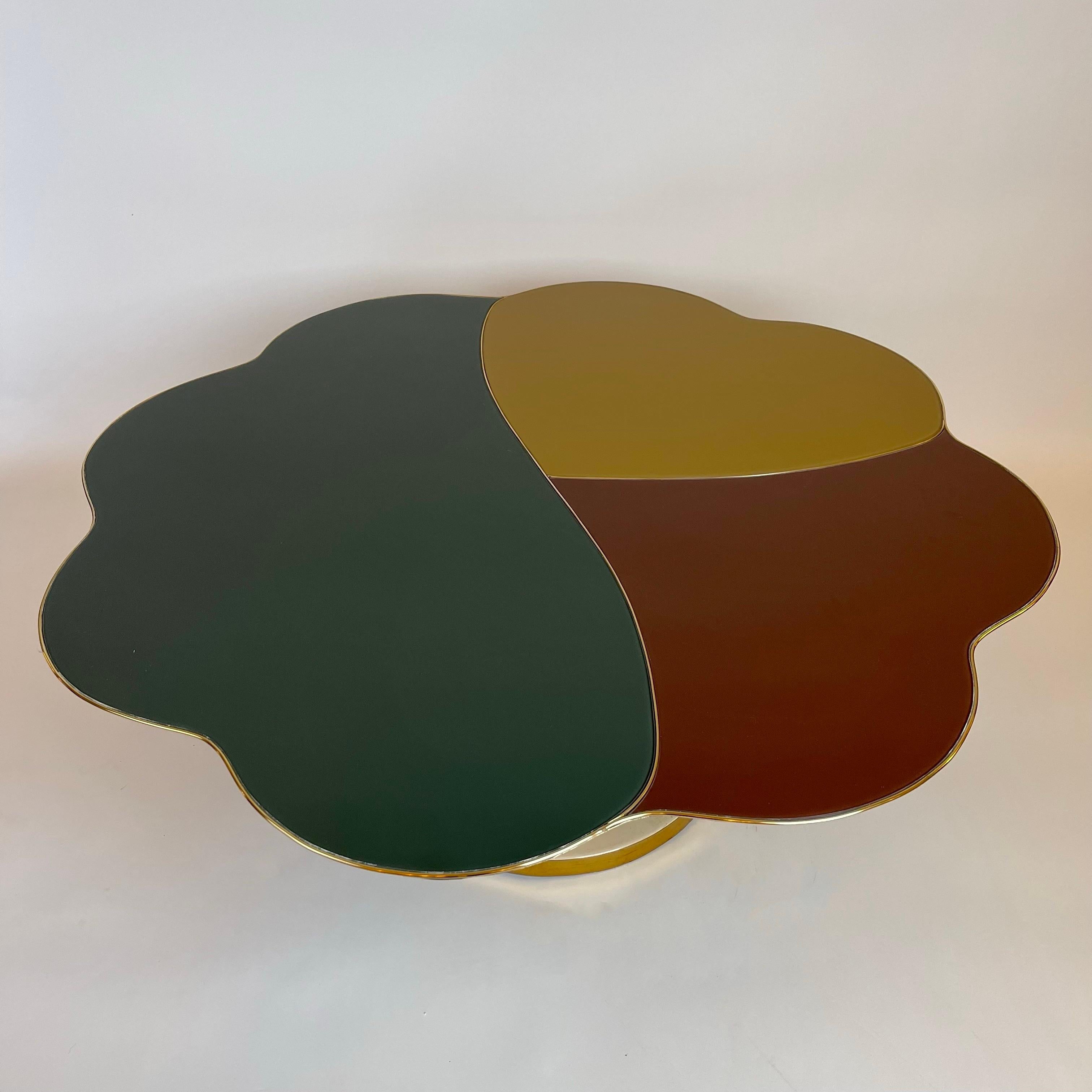 Stunning flower shape coffee table with enameled brass, ceramic balls and brass details basement. The wood top is covered with a marquetry of three colors of opaline glass (mustard, burgundy and dark green) separated from a thin layer of brass and a