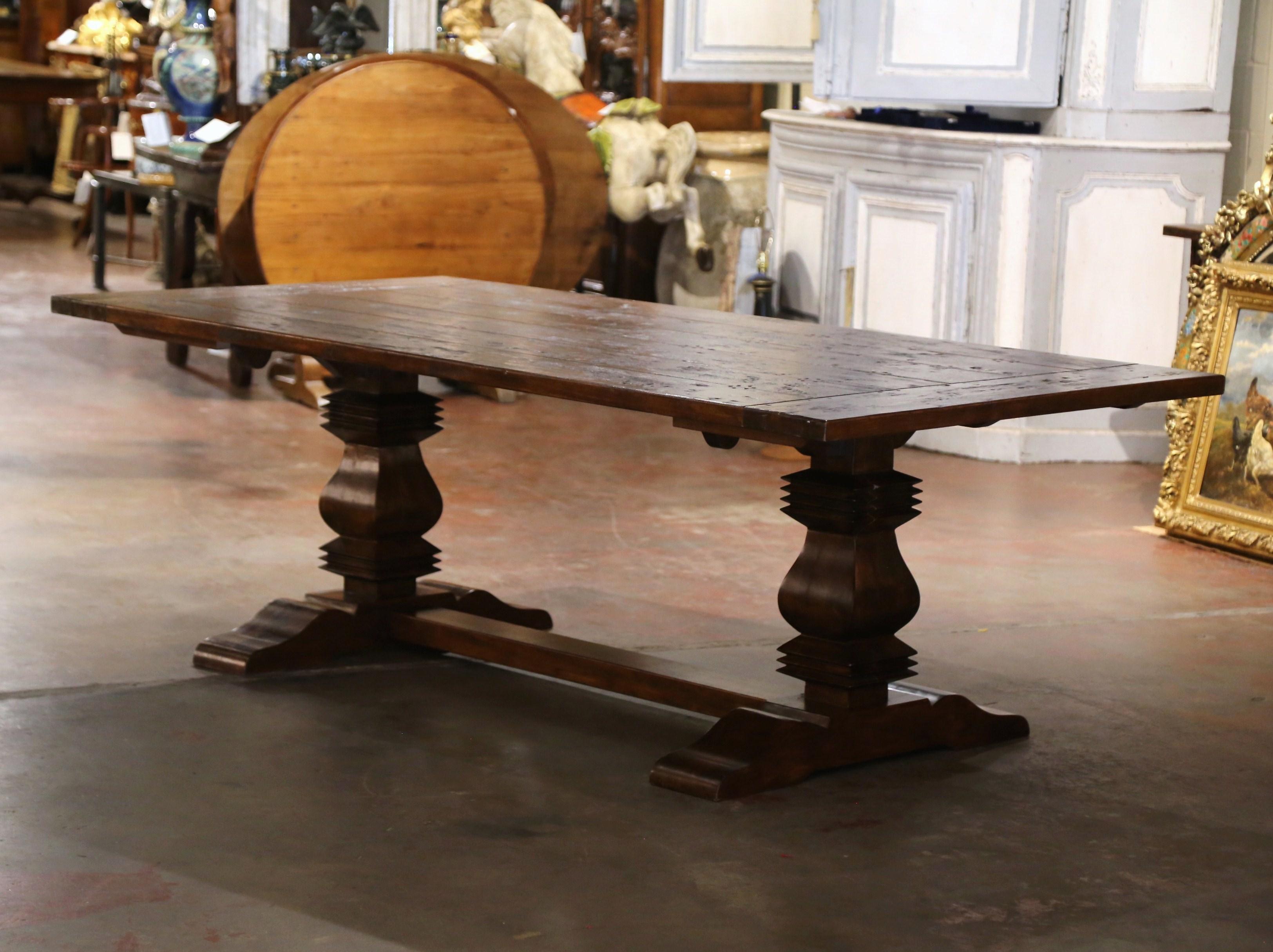 Cette grande table de salle à manger antique de 8 pieds de long a été fabriquée dans le sud-ouest de la France vers 1980. Construite avec des bois anciens et récupérés de chêne et de châtaignier, la lourde table repose sur une élégante base à