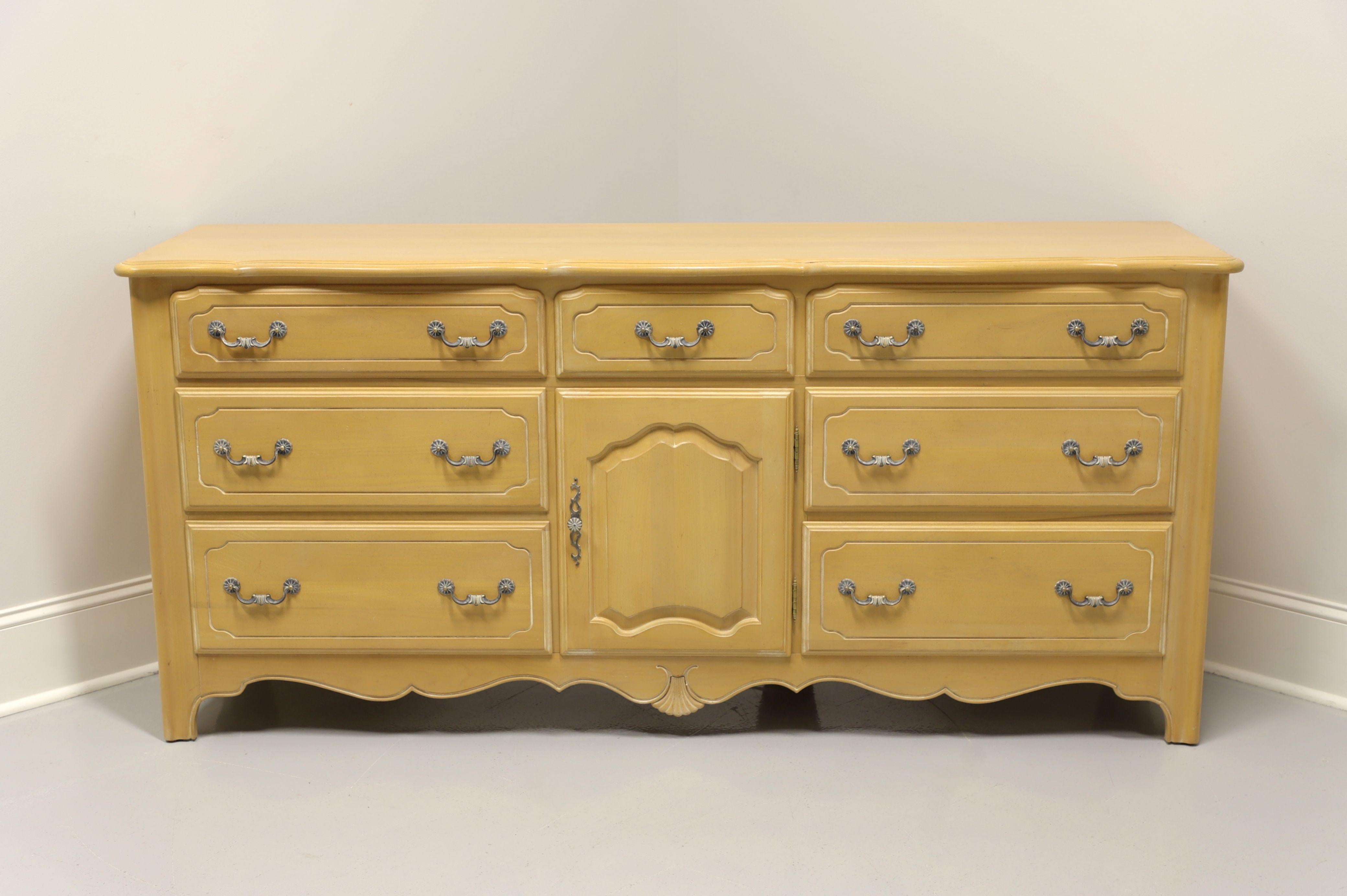 A triple dresser in the French Country style, unbranded, similar quality to Thomasville. Solid hardwood with distressed whitewashed finish and antiqued brass hardware. Features nine dovetail drawers, two of which are behind center cabinet door and