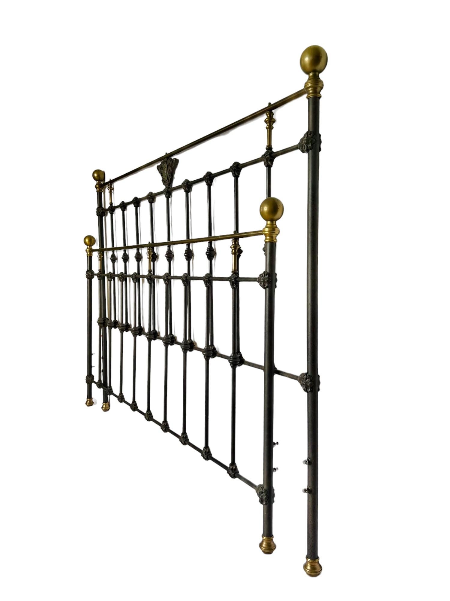 A gorgeous classic French country cast metal king headboard and footboard featuring a steel frame with a powder coated aged dark bronze finish and brass details including post finials, upper crossbars and feet. Anchored bolts for bed frame