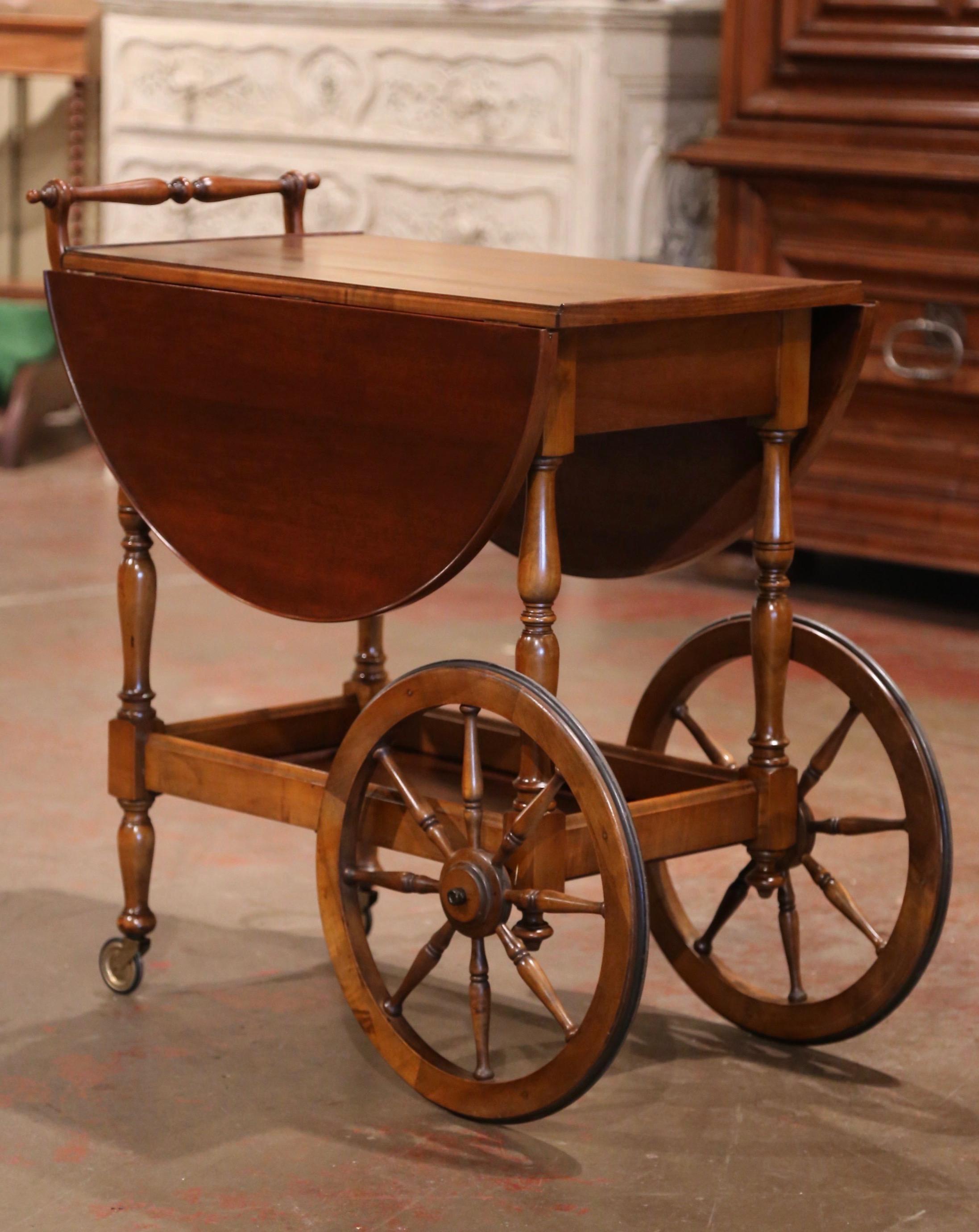 This elegant fruitwood drop-leaf cart was created in France, circa 1980. The cart sits on two large spoked front wheels with rubber, and smaller rear wheels. The two decks are connected with four turned spindles, and is embellished with a decorative