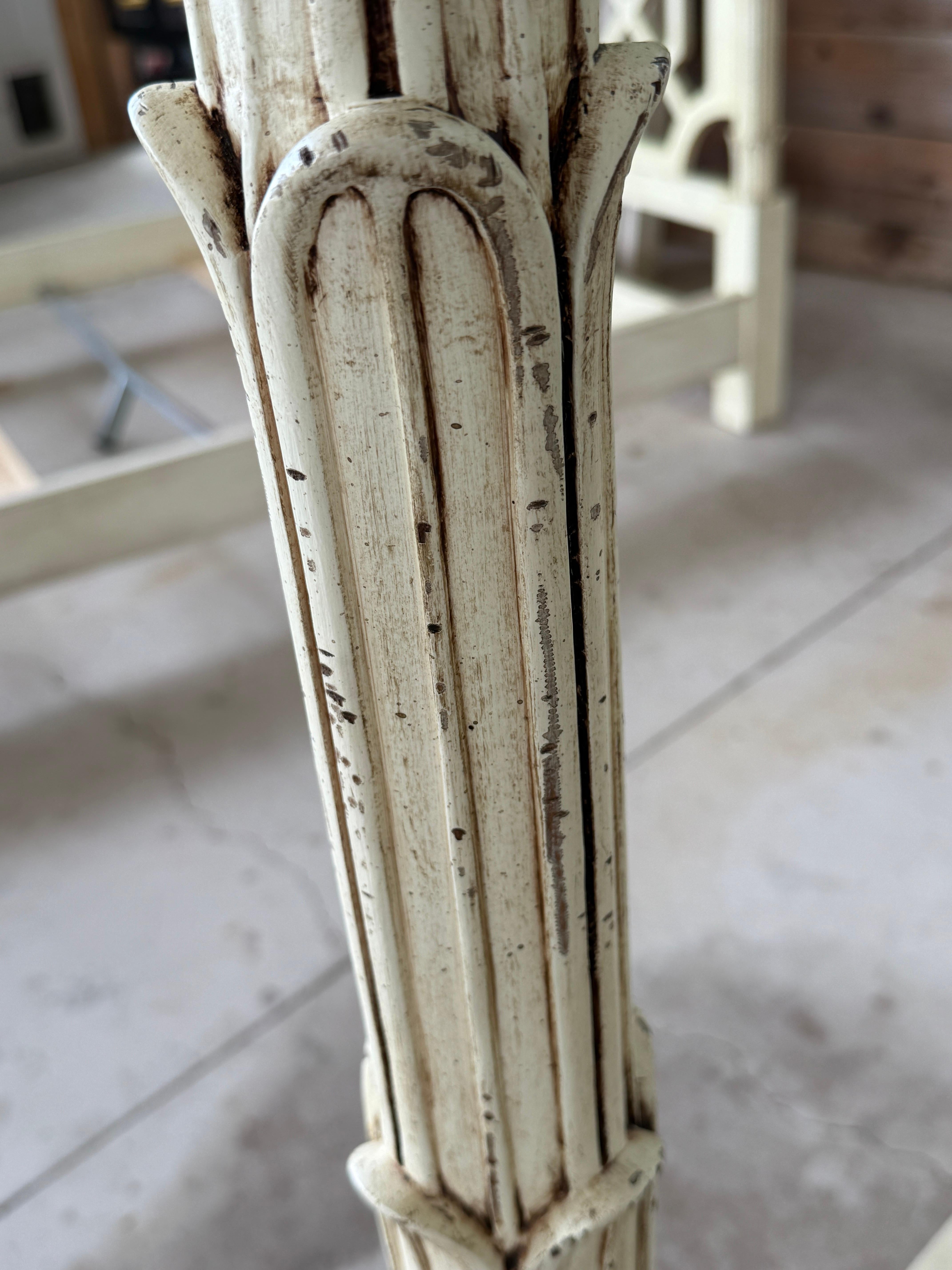 A striking Late 20th Century fretwork canopy queen bed in the manner of Serge Roche, featuring an elegant geometric openwork headboard and intricately carved fluted posts topped with attached sculptural finials.
The aged cream finish enhances its