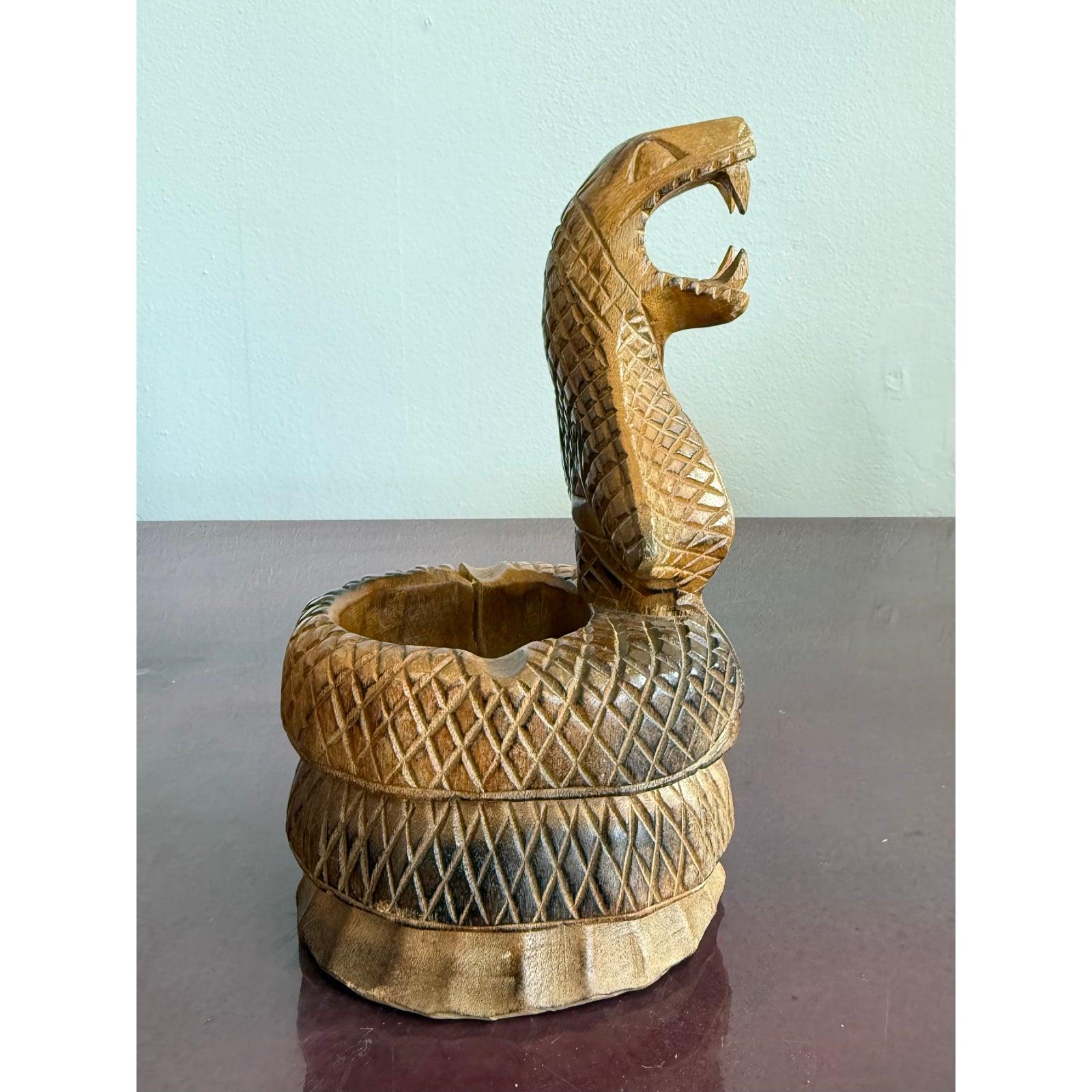 Ce bol en bois sculpté à la main représente un cobra enroulé en pleine attaque, la gueule ouverte et les crocs dévoilés. L'échelle détaillée de la texture et la posture dramatique apportent une présence énergique à n'importe quel espace.