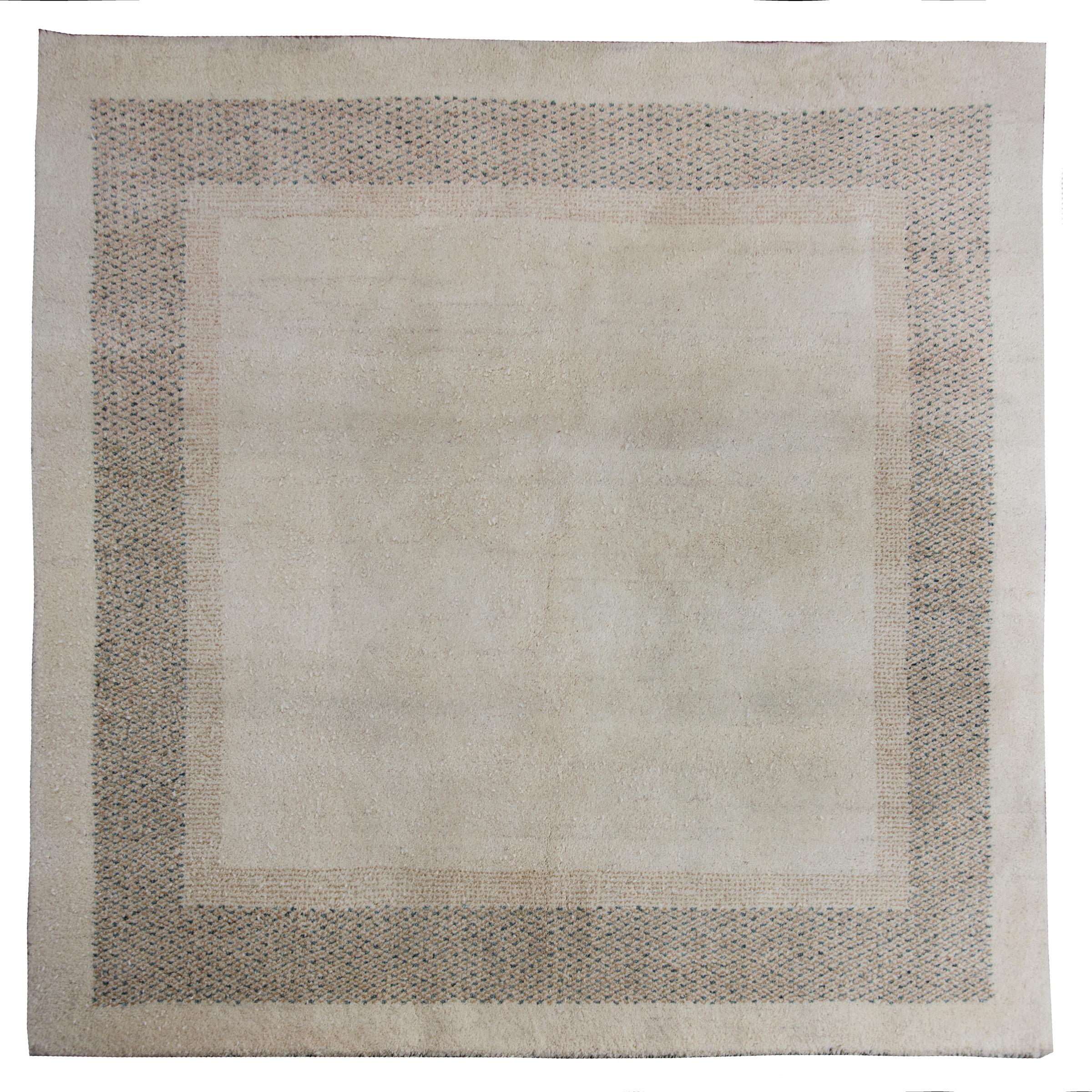 A chic late 20th century Indian Gabbeh-style rug with a solid cream field surrounded by two stippled borders woven with a dark beige and teal colored wool.