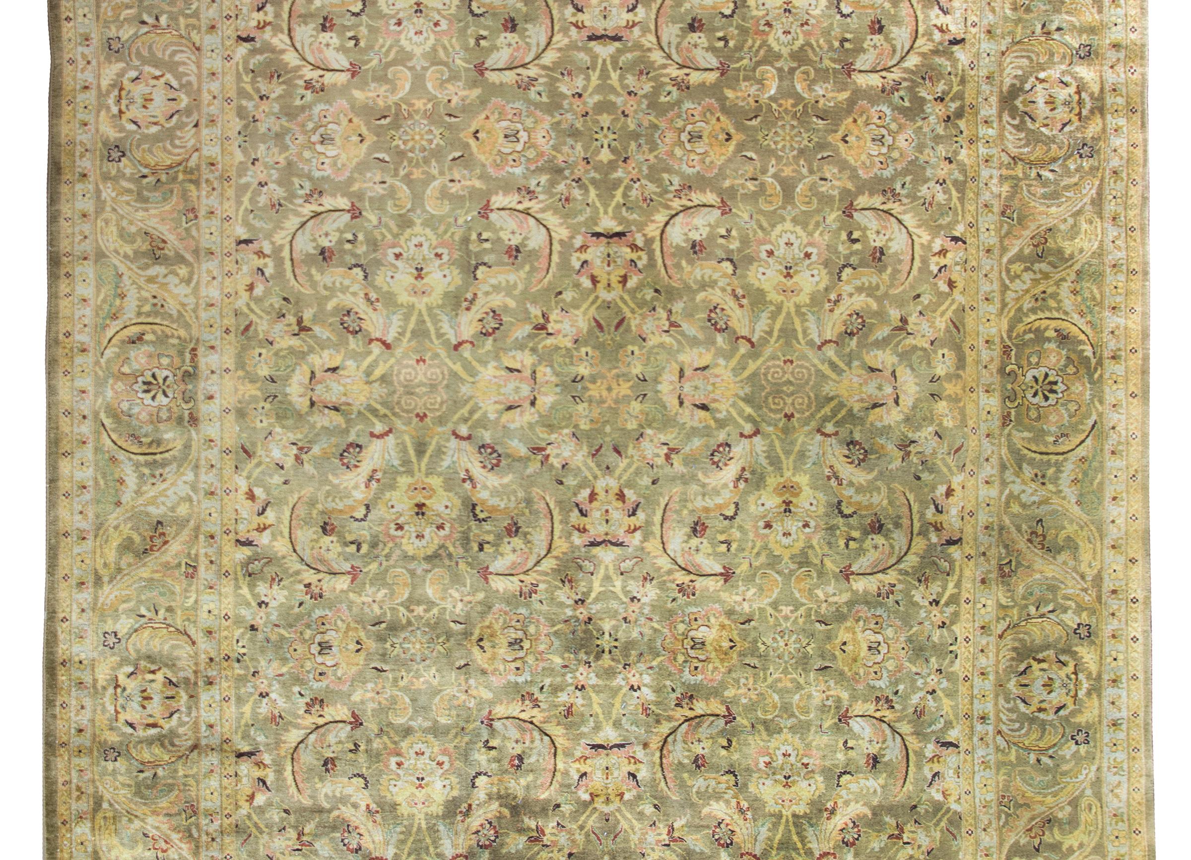 A wonderful late 20th century Indian Oushak rug with an all-over mirrored large-scale floral, leaf, and vine pattern surrounded by a complementary border with more large-scale flowers and all woven in pale yellow, cranberry, pink, and orange, set