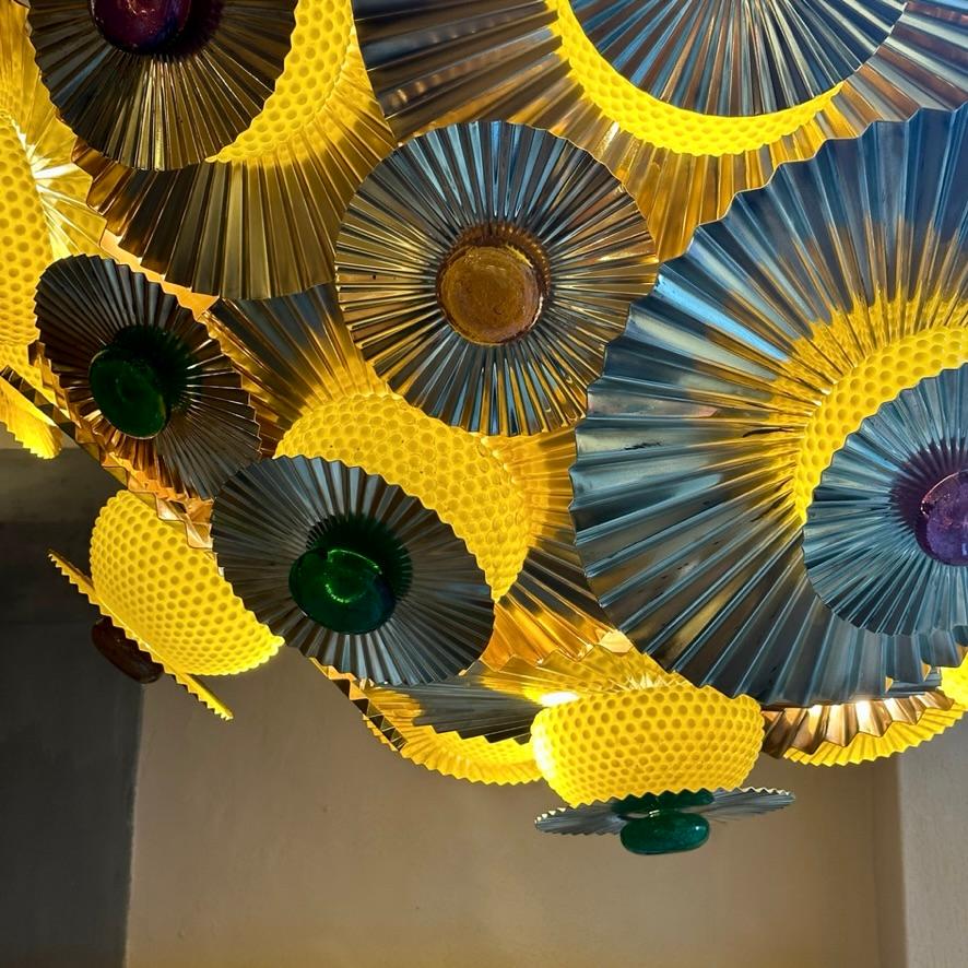 Impressive hemisphere chandelier with round pleated brass disks (two sizes: 50 Diam. & 22 Diam. cm.) with shot peened yellow glasses and multicolored pulegoso Murano glass dots (bordeaux, green & amber).
17 E14 light bulbs under the yellow shot