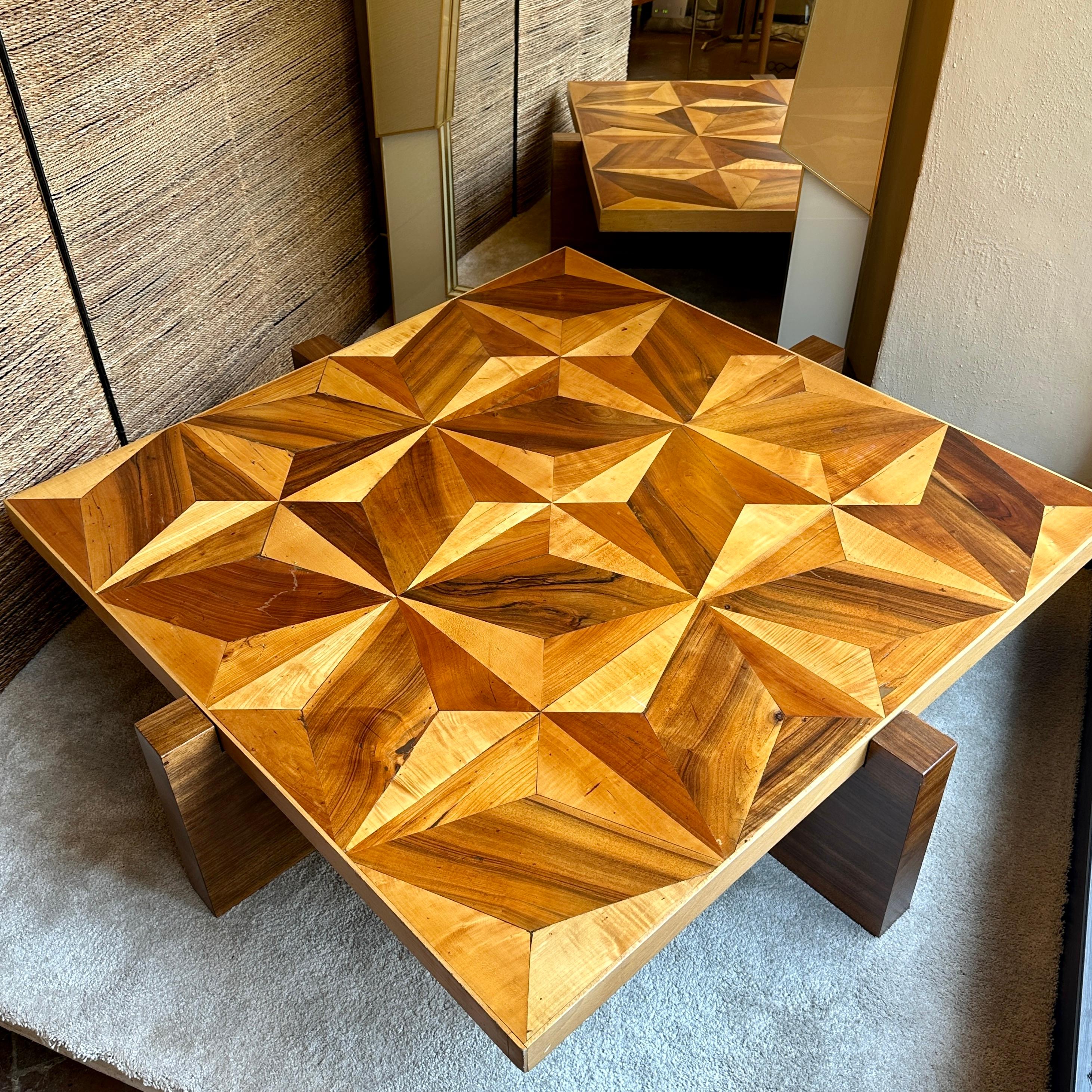 A stunning conversation piece for almost any living room. This coffe table top made with a mix of cherry, walnut, maple and ash wood framed with beech wood (size: 125 x 125 x 5 H cm.) with 5 visible wind roses. Two crossed legs of venereed walnut