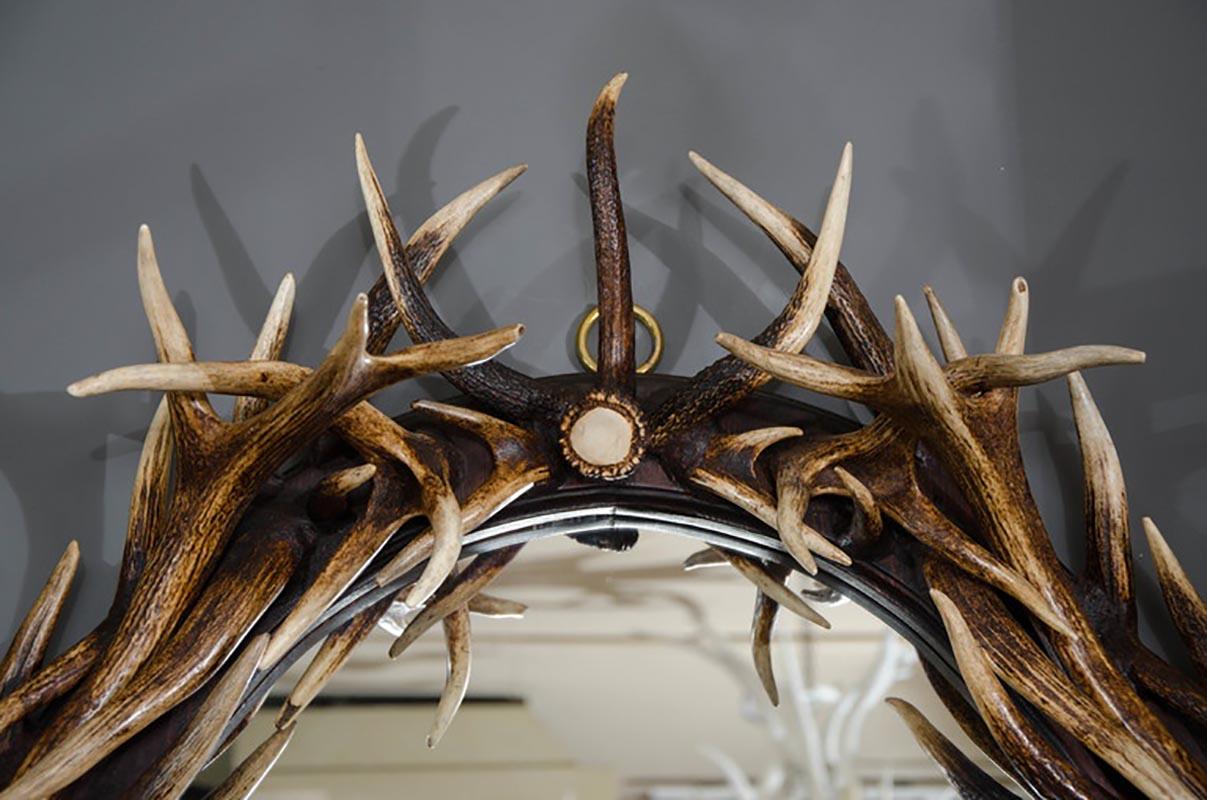 This imposing and unique large oval wall mirror is comprised of naturally shed large red deer from Scotland surrounding an oval mirrored glass center. The individual natural beauty of the antler horn combined with the functionality and artistic