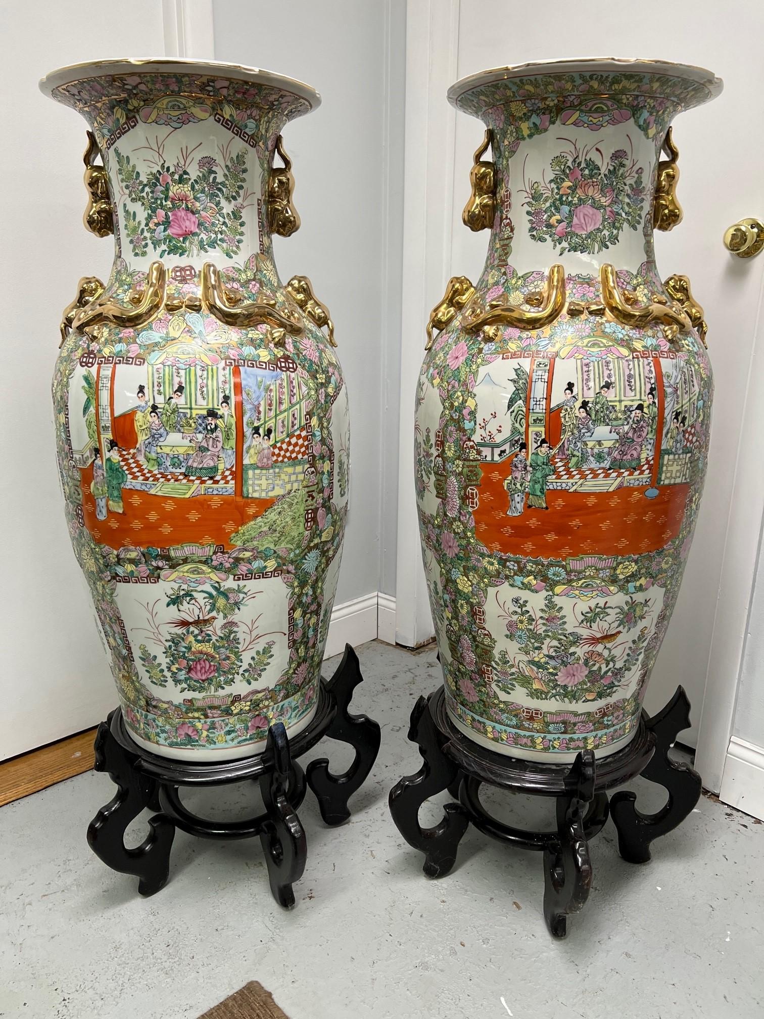 Beautiful pair of hand painted porcelain vases in the style of the Qing Dynasty each with two panels of hand painted figures. The vases sit on top of wood pedestals that would look great as accent pieces in any room of your home. Sold only as a pair