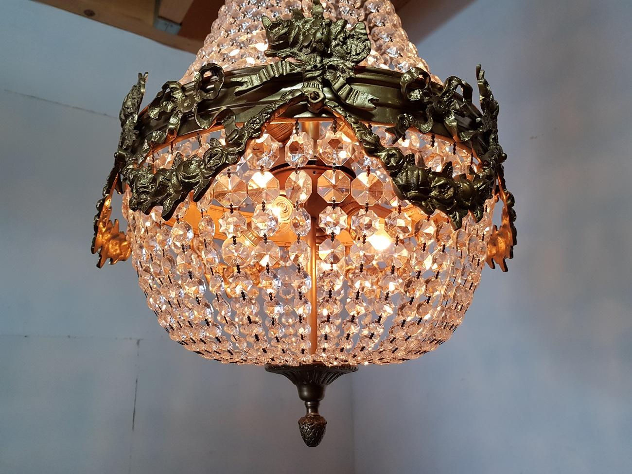 Heavy 8 lights crystal chandelier in Louis XVI style with gold colored metal frame decorated with garlands and bows in very good condition, late 20th century.

The measurements are,
Depth 50 cm/ 19.6 inch.
Width 50 cm/ 19.6 inch.
Height 93 cm/