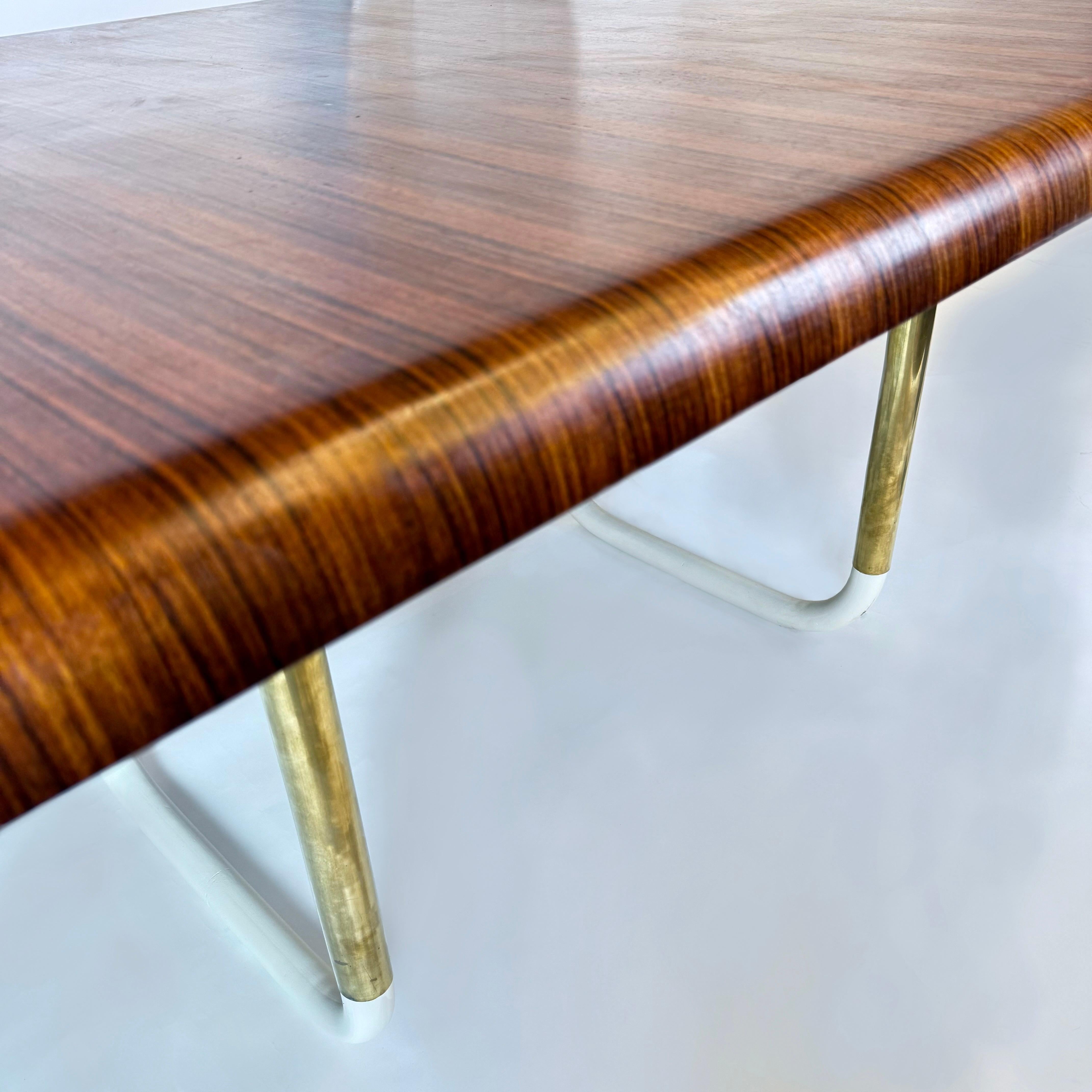 Elegantísimo tablero de mesa de comedor chapado en ébano de Macassar (acabado barniz mate) y basamento de hierro pintado de blanco. Las patas tubulares de la mesa tienen detalles de latón que realzan el aspecto del objeto. El tablero de la mesa se