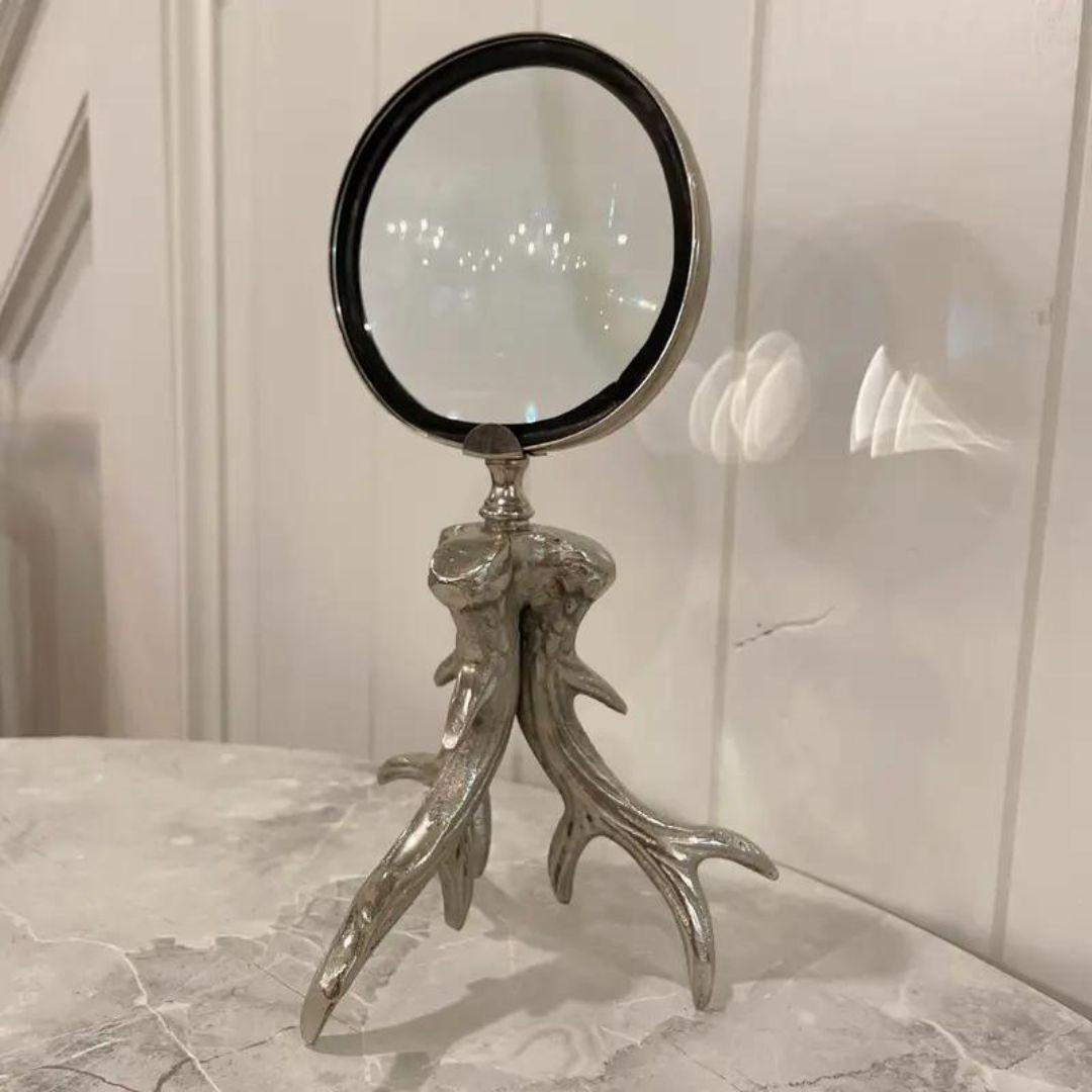 Gorgeous standing magnifying glass with metal surround and metal antler detail, sitting on a antler horn tripod base. The glass in great condition. Great for the office or on a shelf!