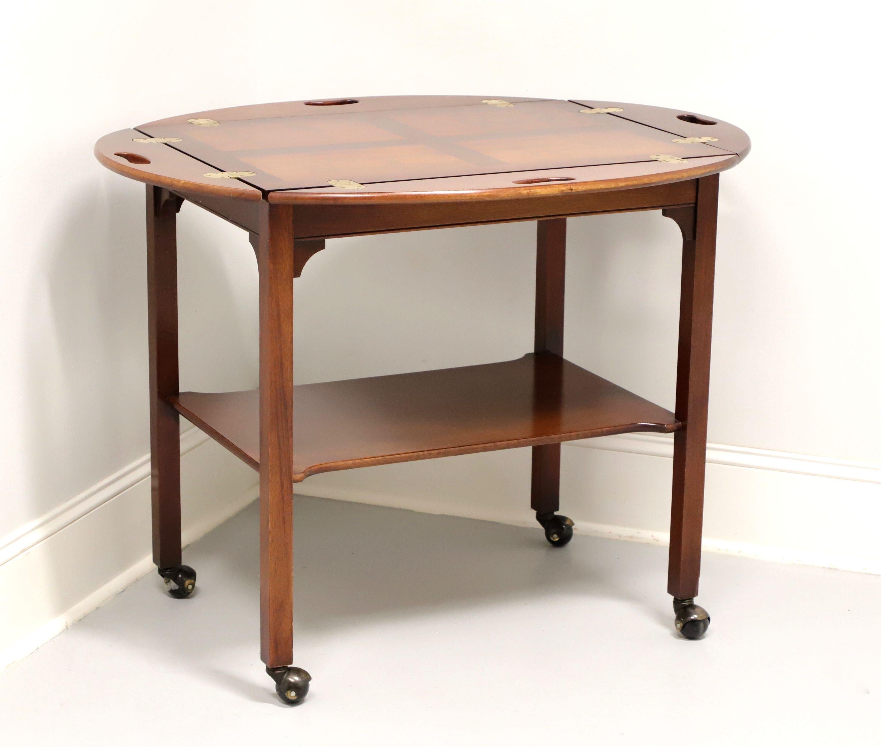 A Chippendale style Butler's cart, unbranded, likely Hickory Furniture Company. Mahogany with cross banded inlaid yew wood top, brass hinge hardware, under tier shelf, straight legs, and on casters. Features four fold down sides with carved open