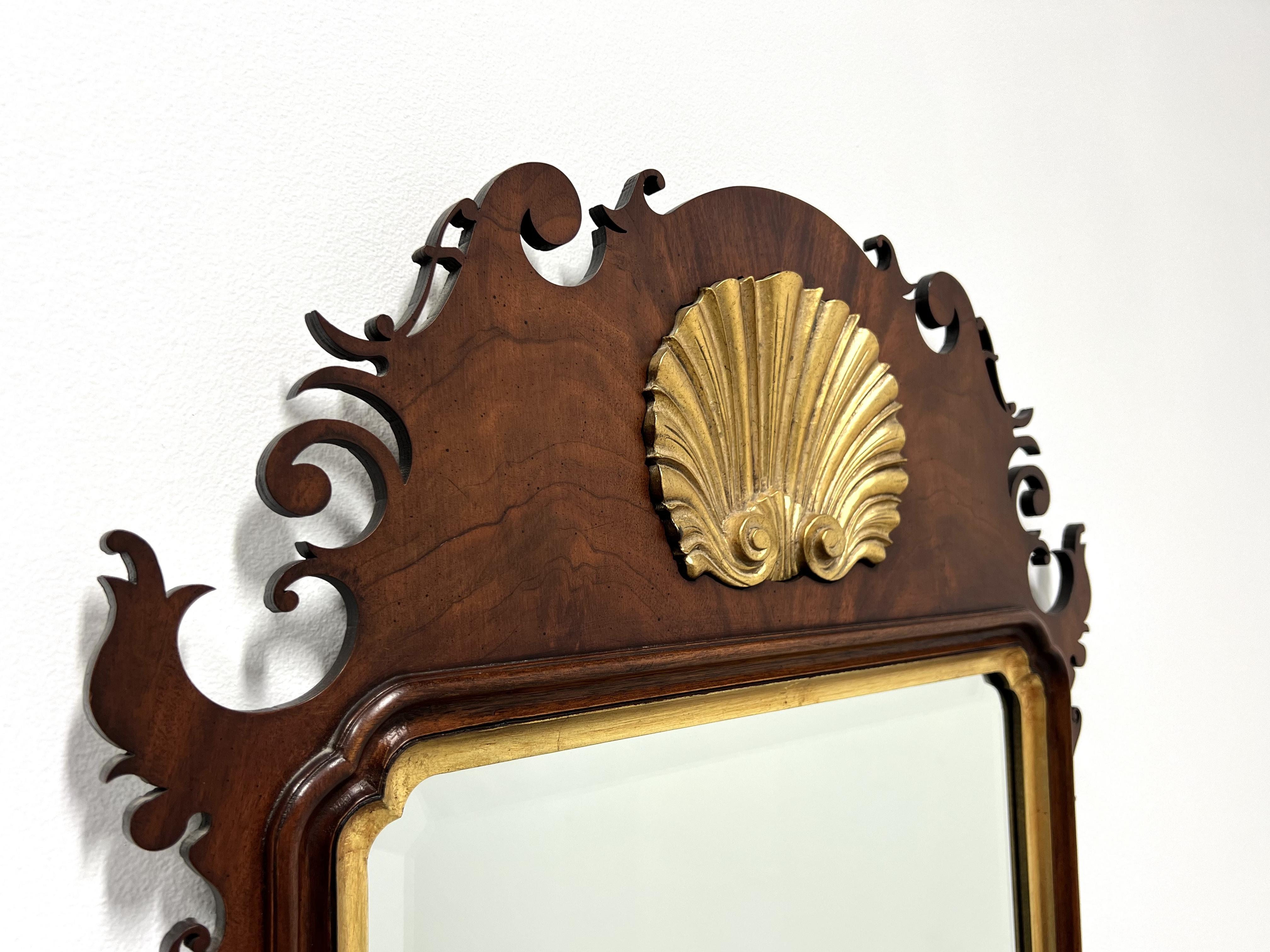 A Chippendale style wall mirror, unbranded, similar quality to Councill or Lexington. Bevel edge mirrored glass in a mahogany frame with gold trim and top center gold gilt shell shaped medallion. Made in the USA, in the late 20th Century.

Measures: