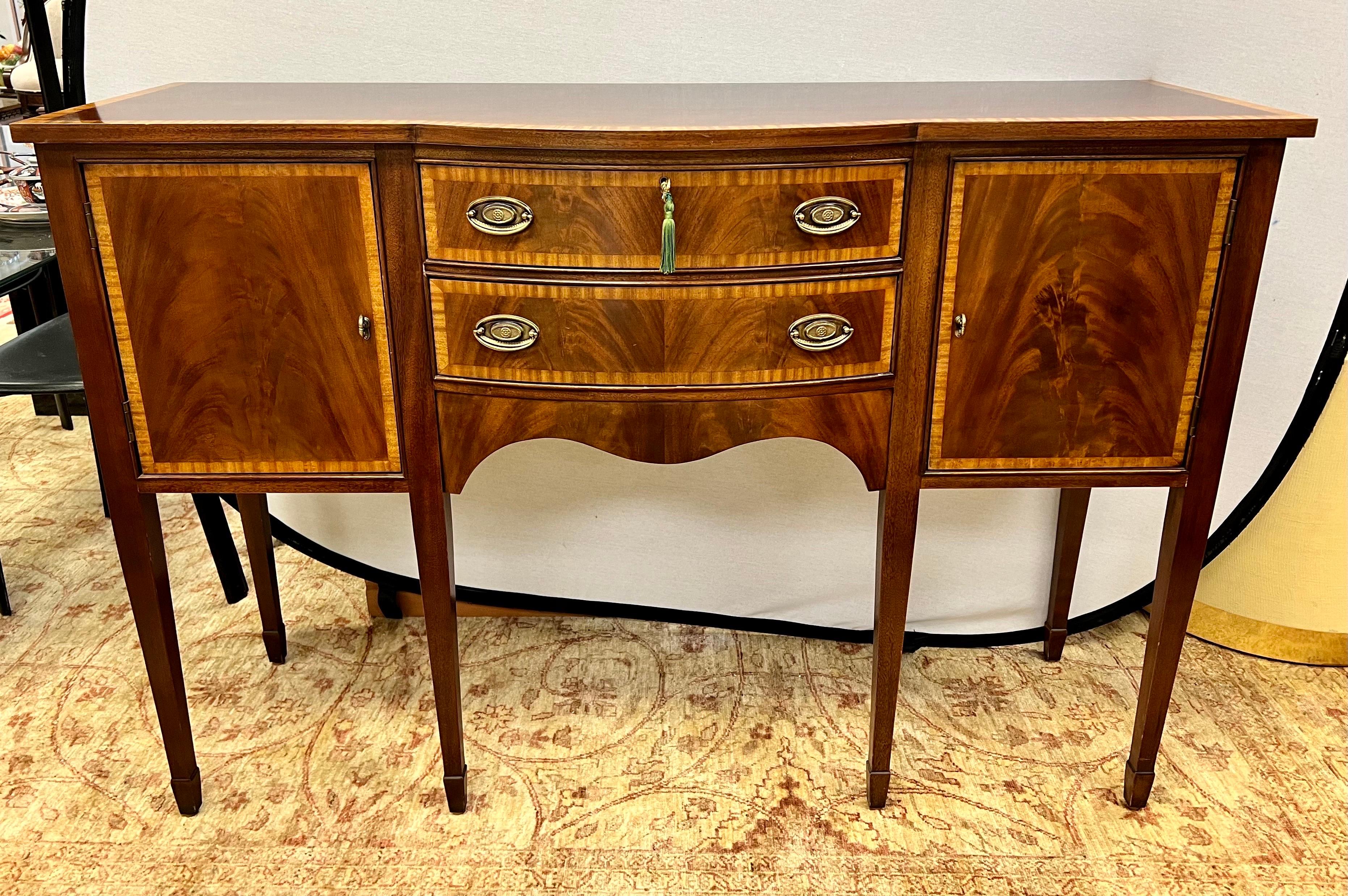 Elegant mahogany sideboard/buffet that features ribbon inlay on top, doors and two drawer front, and incredible craftsmanship. Supported on six tapered legs. Felt silver liner in top drawer for your sterling. Working lock and key present and