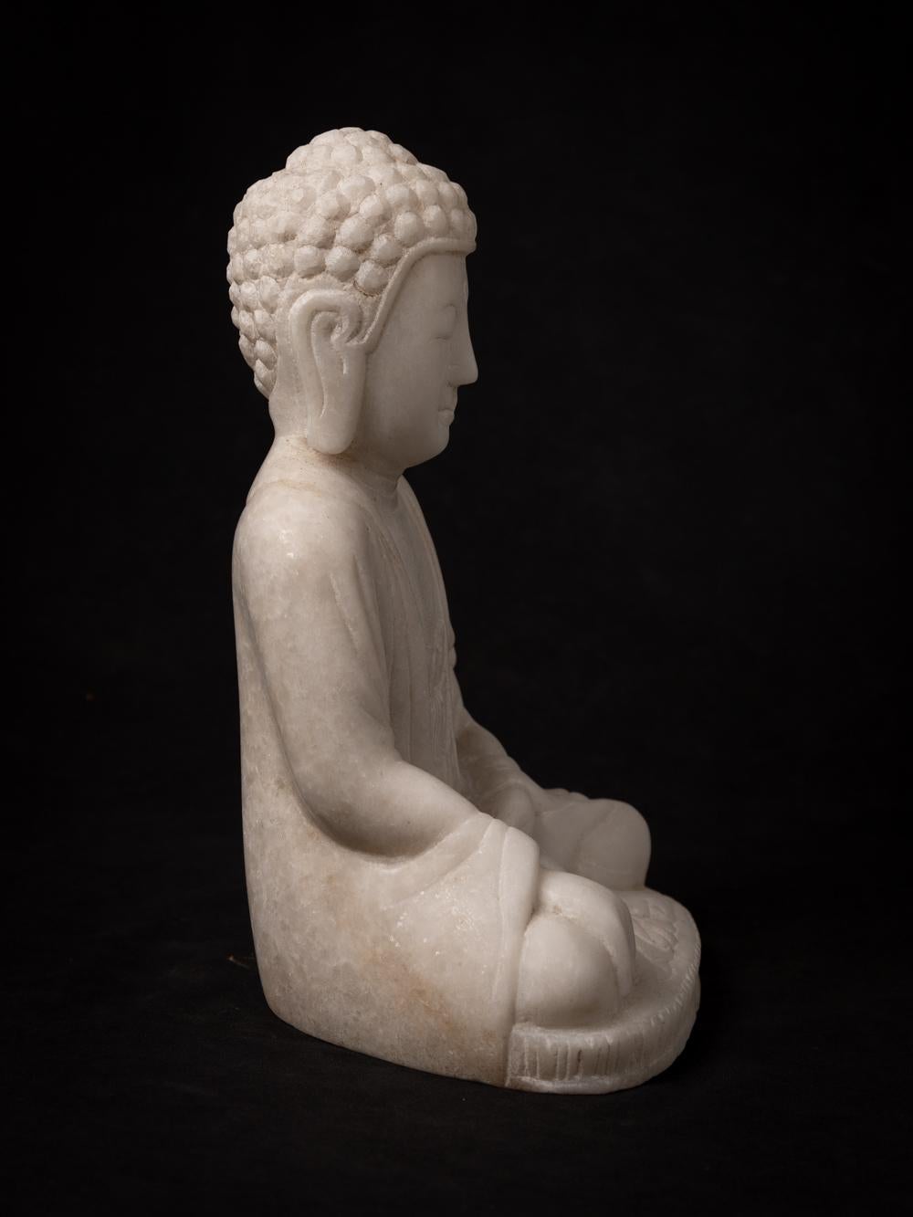 This elegant Marble Buddha statue, portraying the Bhumisparsha mudra, is a work of art that stands at 28.5 cm in height, with dimensions of 19 cm in width and 14.7 cm in depth. Carved by hand from a single block of white marble, it represents a