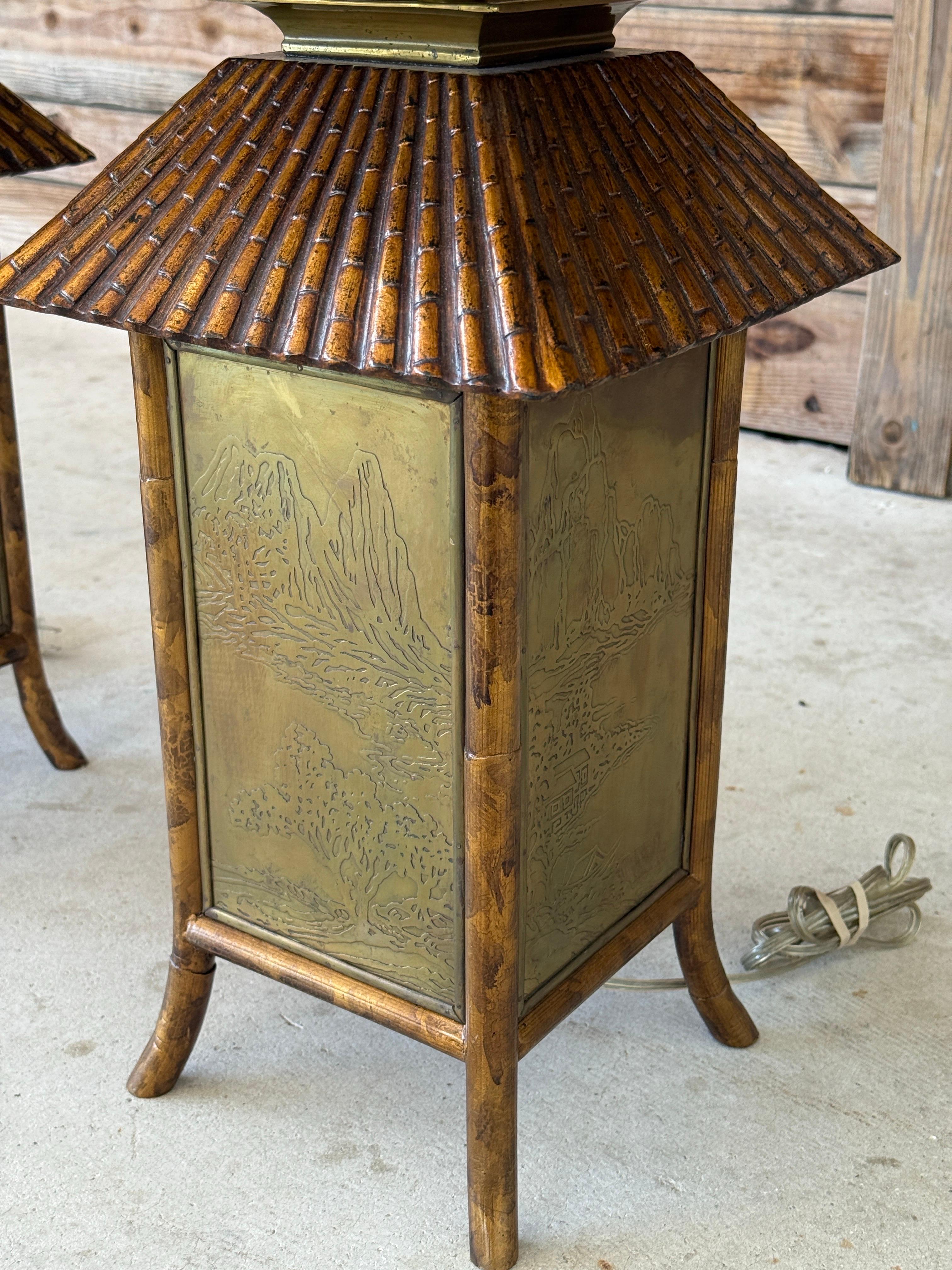 Une paire saisissante de lampes de table mixtes présentant des silhouettes de style pagode avec un encadrement en faux bambou dans une finition en résine coulée, richement peinte dans des tons d'or et de bronze brûlés.
Chaque côté est incrusté de