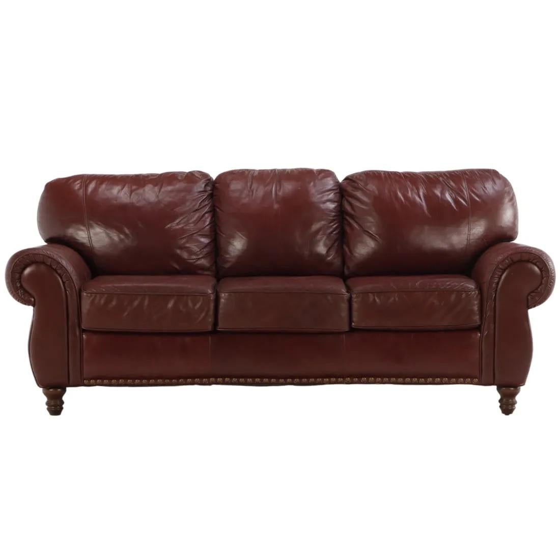 Un luxueux canapé en cuir cognac avec d'élégants accoudoirs à volutes agrémentés avec goût d'une garniture en tête de clou.