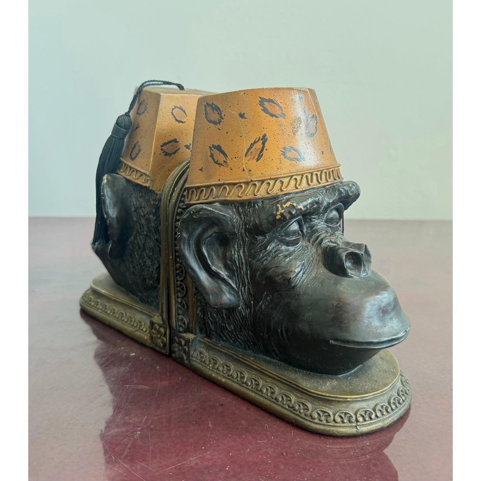 Unconventional and humorous, these sculptural bookends feature detailed monkey heads wearing fez hats that double as candles. The bold headwear is decorated with kiss mark patterns, one topped with a black tassel. The monkeys’ expressions and