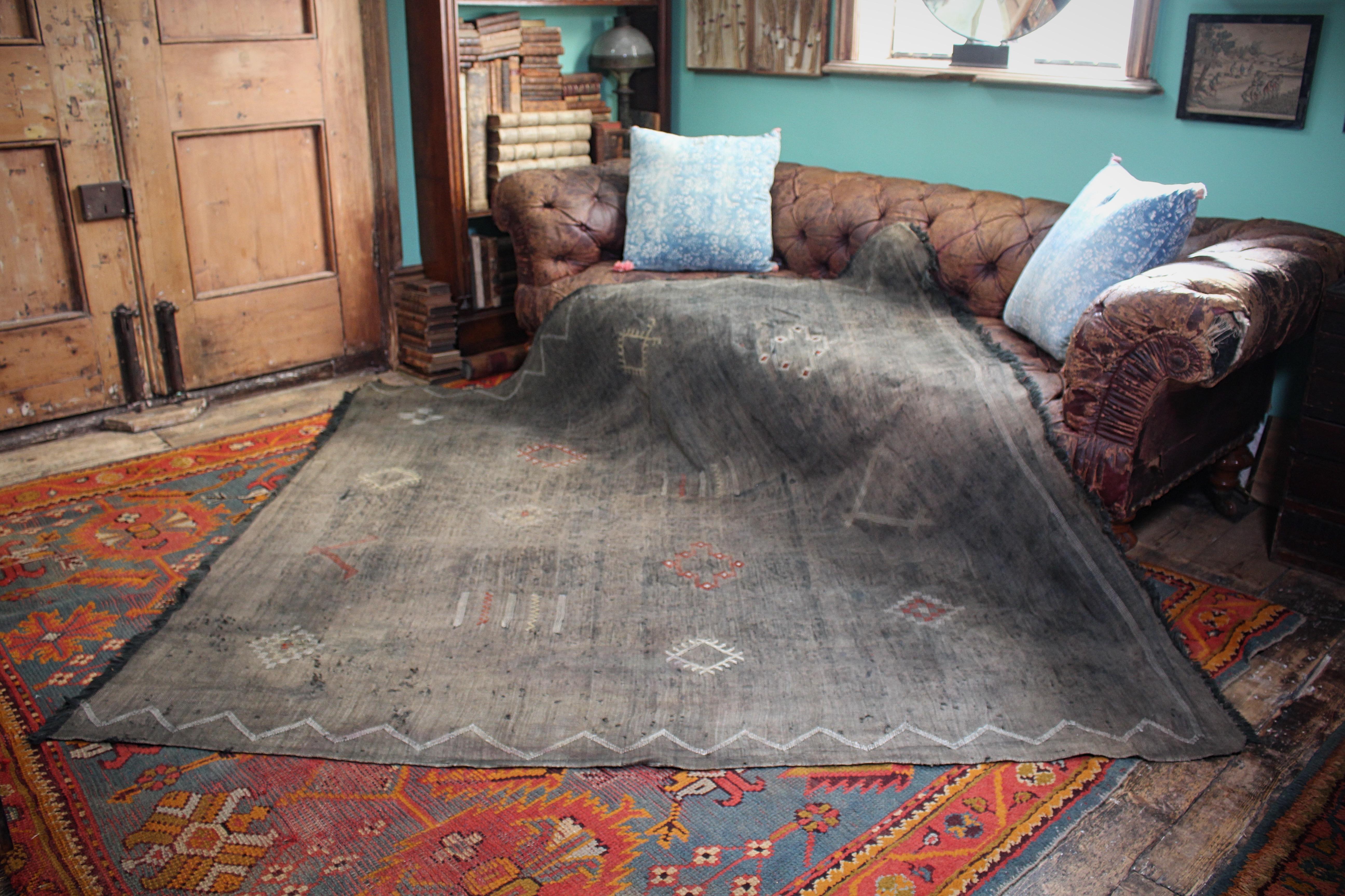 Beautiful handwoven rug made of cactus silk with a multicoloured geometric pattern on a black ground.

The rug is nicely worn and faded from use, with some heavy wear to the edgers and some holes please refer to  the photographs. Some elderly carpet