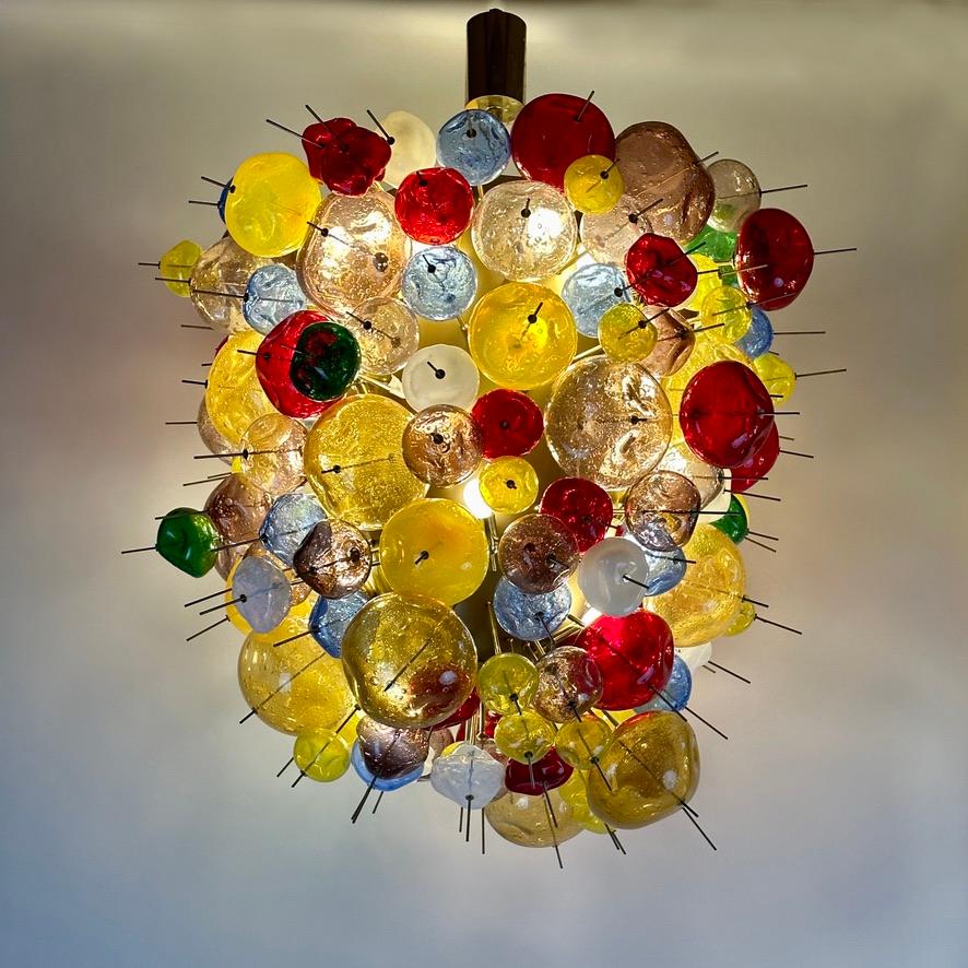 Stunning space age clustering of multicolored (lemon yellow, amber, violet, red, green, blue and white) Pulegoso Murano glass crushed balls, painted metal & brass pendant chandelier. 

E14 Light Bulbs

Short History of the inventor of the Pulegoso