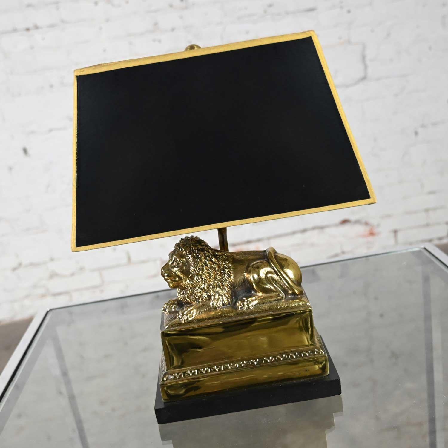 Atractiva lámpara de escritorio neoclásica vintage con león de latón, pantalla rectangular de cartón negro con adornos dorados, difusor en la pantalla, cable negro con interruptor en línea, vástago chapado en latón, león y remate de latón, y base de