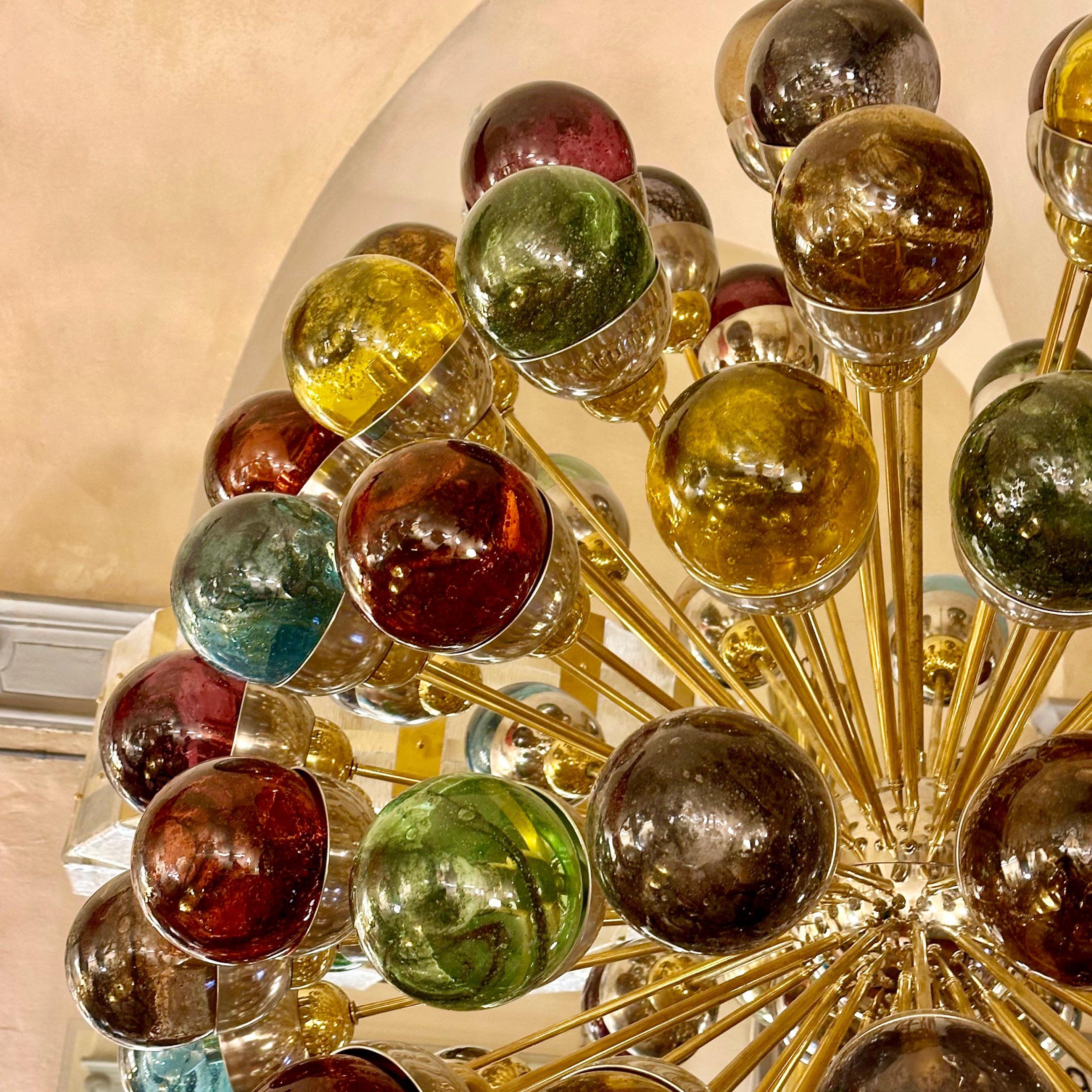 Stunning nickel & brass sputnik chandelier with multicolored Murano blown Pulegoso art glass boules. Color mix: purple, yellow, green, amber, light blue, gray, brown and red amber.
The glass boules are kept into place with brass clips. Sputnik