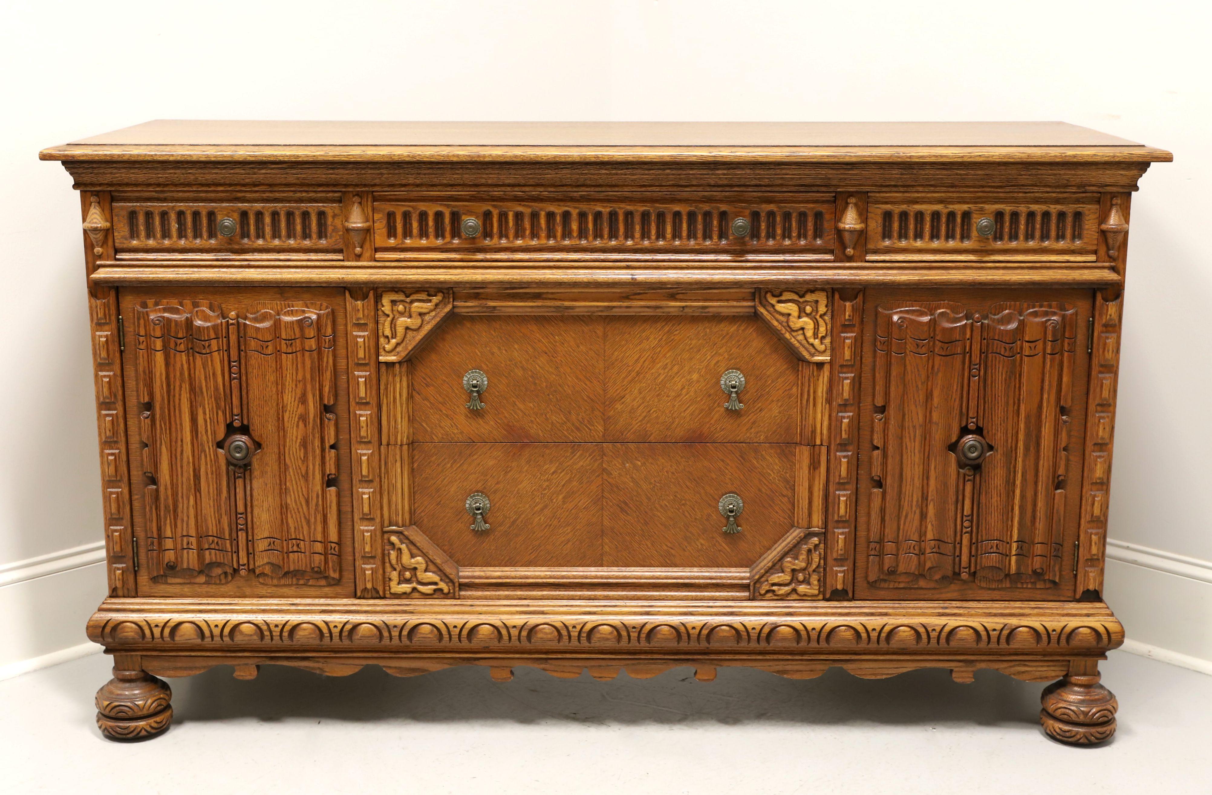 A late 20th century reproduction of a Jacobean Revival style sideboard, unbranded. Oak and oak veneers, decorative metal hardware, carved upper drawer & door fronts, inlaid lower drawer fronts, carved sides & apron and carved bun front feet.