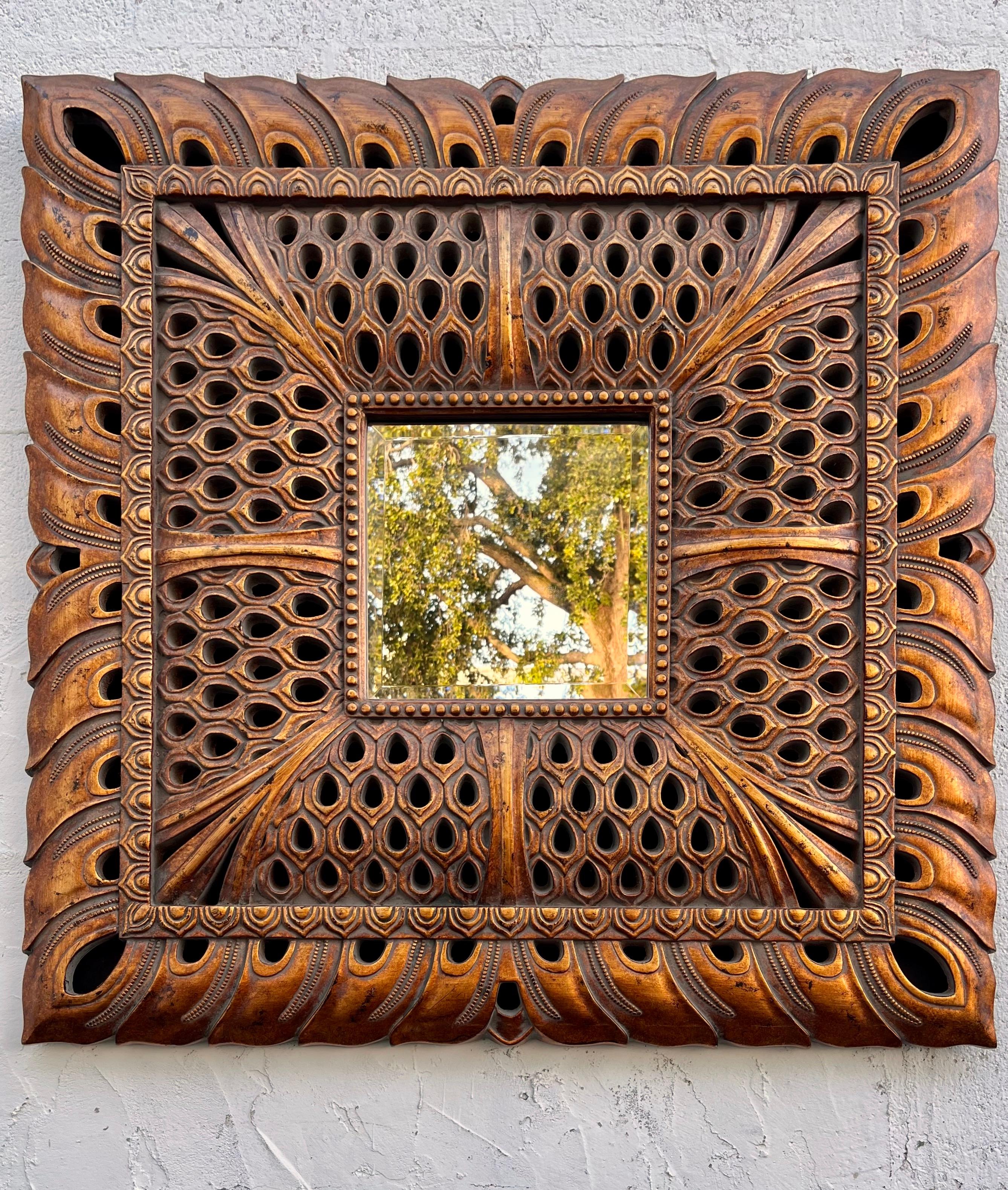 Fin du 20e siècle Miroir orné en résine. Circa 1990 
Elle présente un grand cadre de style Syroco imitant le bois sculpté d'inspiration asiatique, fini avec une patine dorée antique, et un miroir carré biseauté. 
Il peut être suspendu