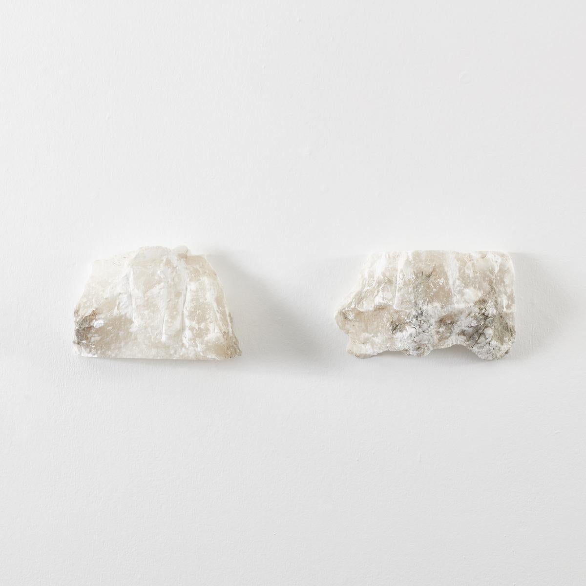 This pair of large rough-hewn alabaster wall sconces have a great presence to them. They are made from thick pieces of alabaster stone with rough-cut edges and chisel marks. Alabaster is known for its ethereal translucence, allowing light to glow