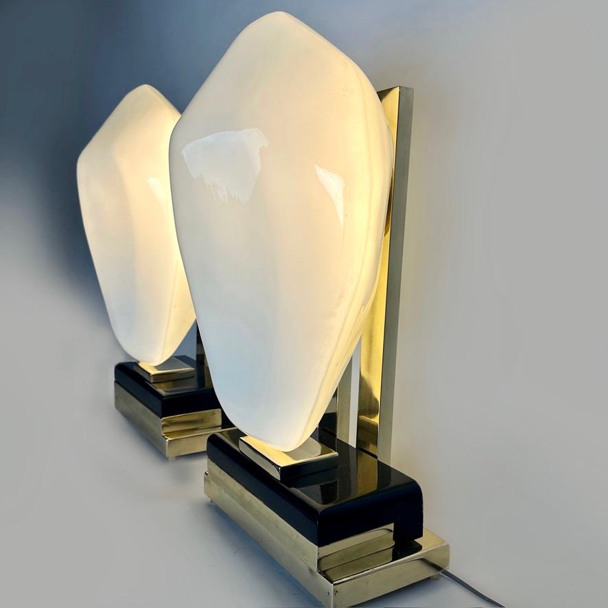 This pair of modern table lamps with faceted amorphous white Murano glass diffusers fit almost any kind of environment and they are perfect to be placed on night stands or for any leaving room.
The mix of black painted iron, brass & white Murano art