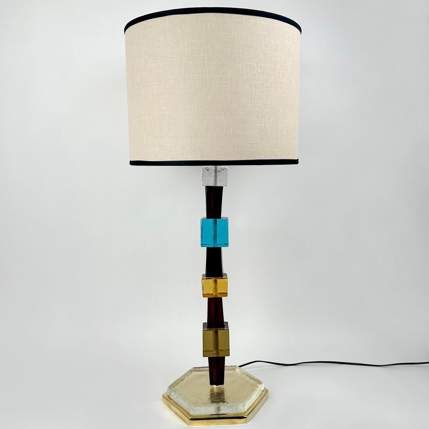 Cette paire de lampes de table en laiton avec du verre d'art de Murano multicolore (transparent, ambre, fumé, marron et turquoise) s'adapte à presque tous les environnements modernes.
Le mélange de pyramides tronquées et de cubes en laiton et en