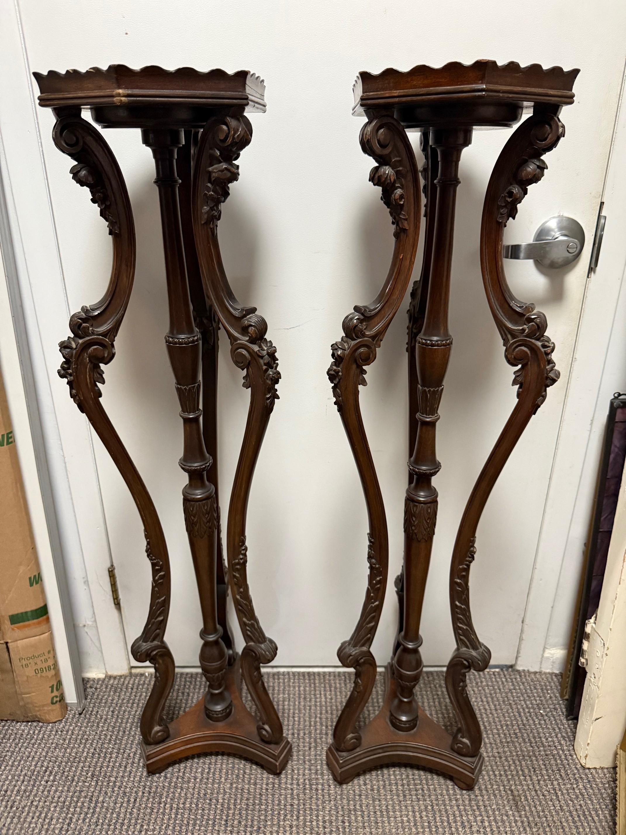 Fin du 20ème siècle, paire de supports de plantes ou de piédestaux en bois sculpté en acajou. Il s'agit d'une grande et élégante paire de pupitres (ou supports de plantes) soutenus par trois pieds sculptés. Les pieds sont sculptés de feuilles