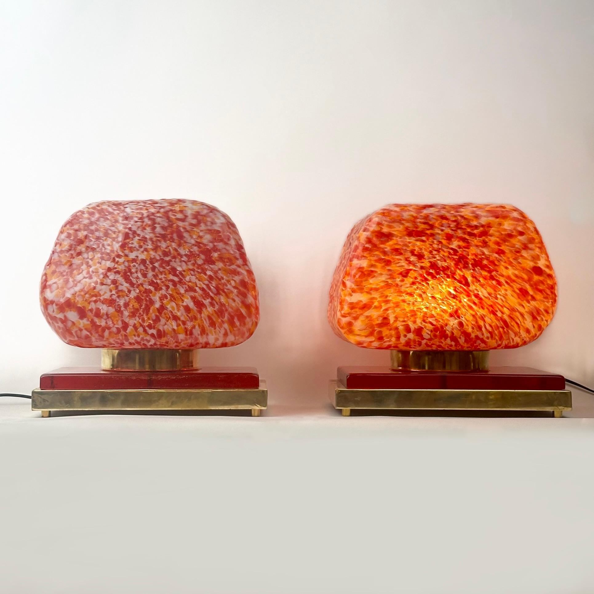 Cette paire de lampes de table sculpturales modernes s'adapte à presque tous les types d'environnement et est parfaite pour les tables d'appoint de la chambre à coucher.
Le mélange de laiton et de verre rouge de Murano avec des diffuseurs en verre