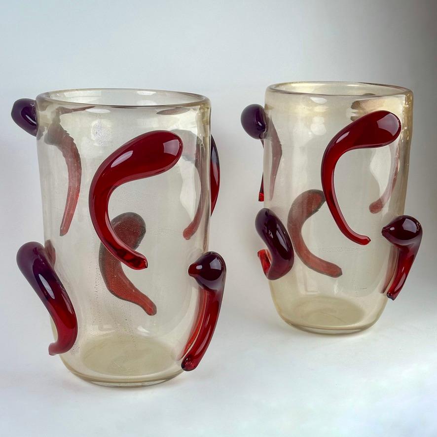 Paire de vases en verre d'art de Murano de la fin du 20e siècle, d'une transparence étonnante et brillante avec des paillettes d'or. Les applications rouges en verre d'art de Murano, semblables à des têtards, rehaussent la beauté des vases qui