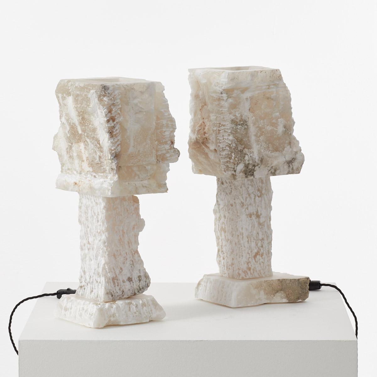 This pair of large rough-hewn alabaster table lamps has a great presence. The surfaces are made from thick slabs of alabaster stone with rough-cut edges and chisel marks. Alabaster is known for its ethereal translucence, allowing light to glow