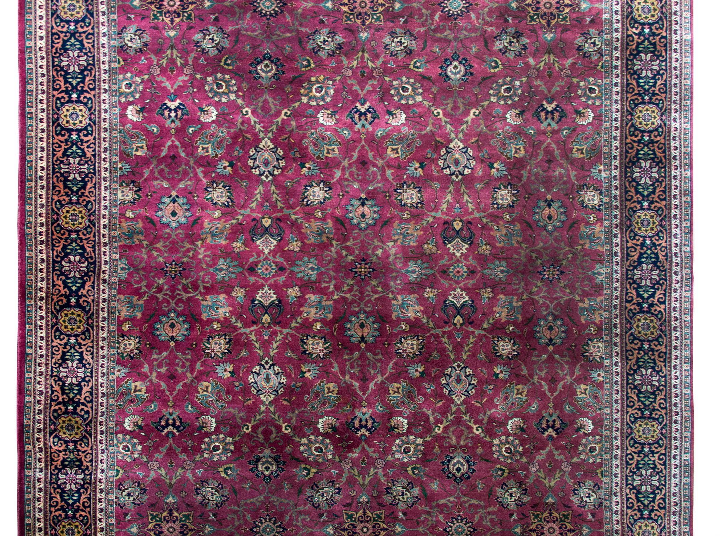 A wonderful late 20th century Pakistani Tabriz-style rug with an al-over mirrored floral trellis pattern woven with large-scale flowers, scrolling vines, all surrounded by a complex border with a wide central stripe with a repeated floral pattern