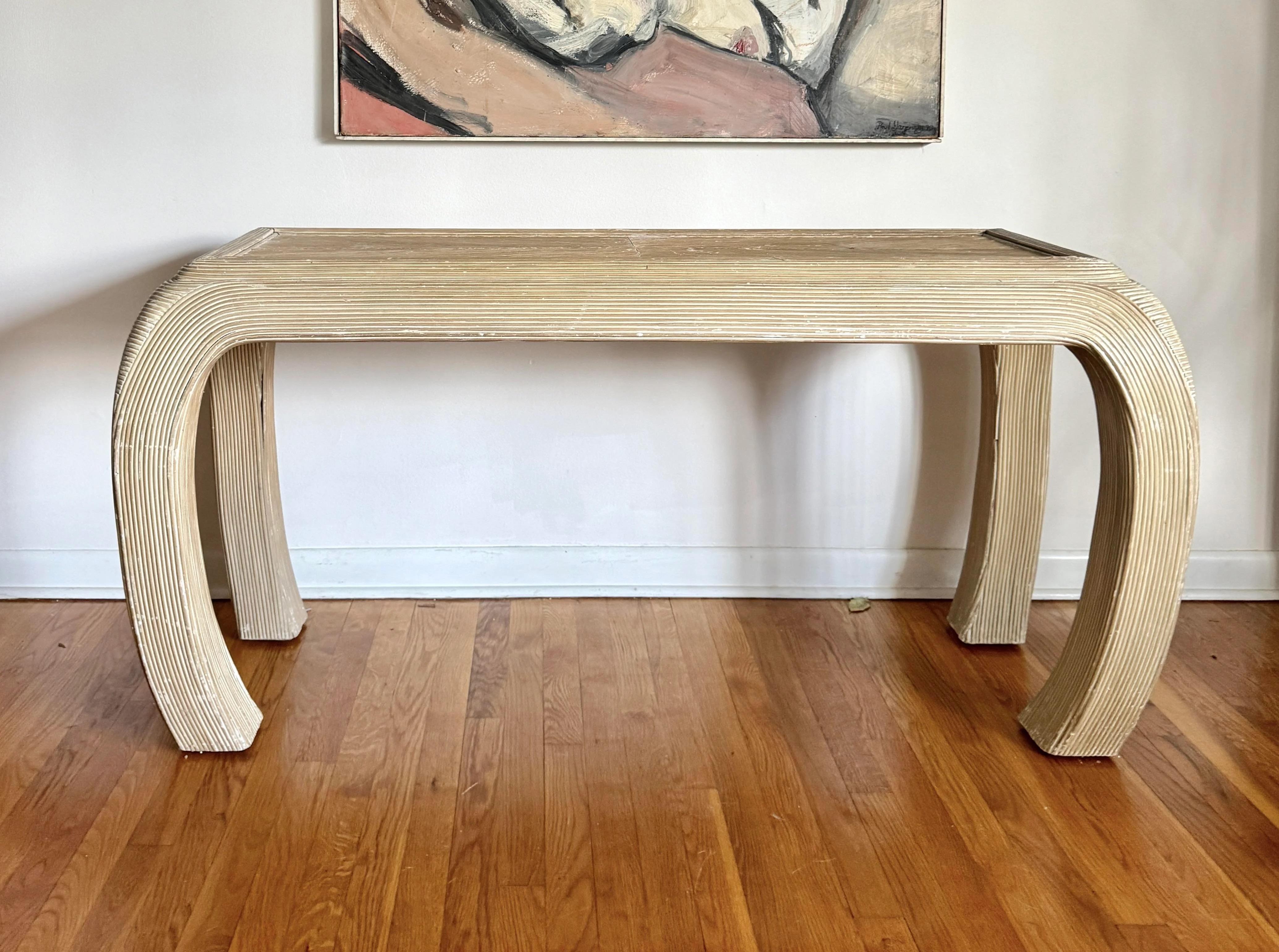 A stunning vintage, curved pencil rattan console table in the manner of Karl Springer.