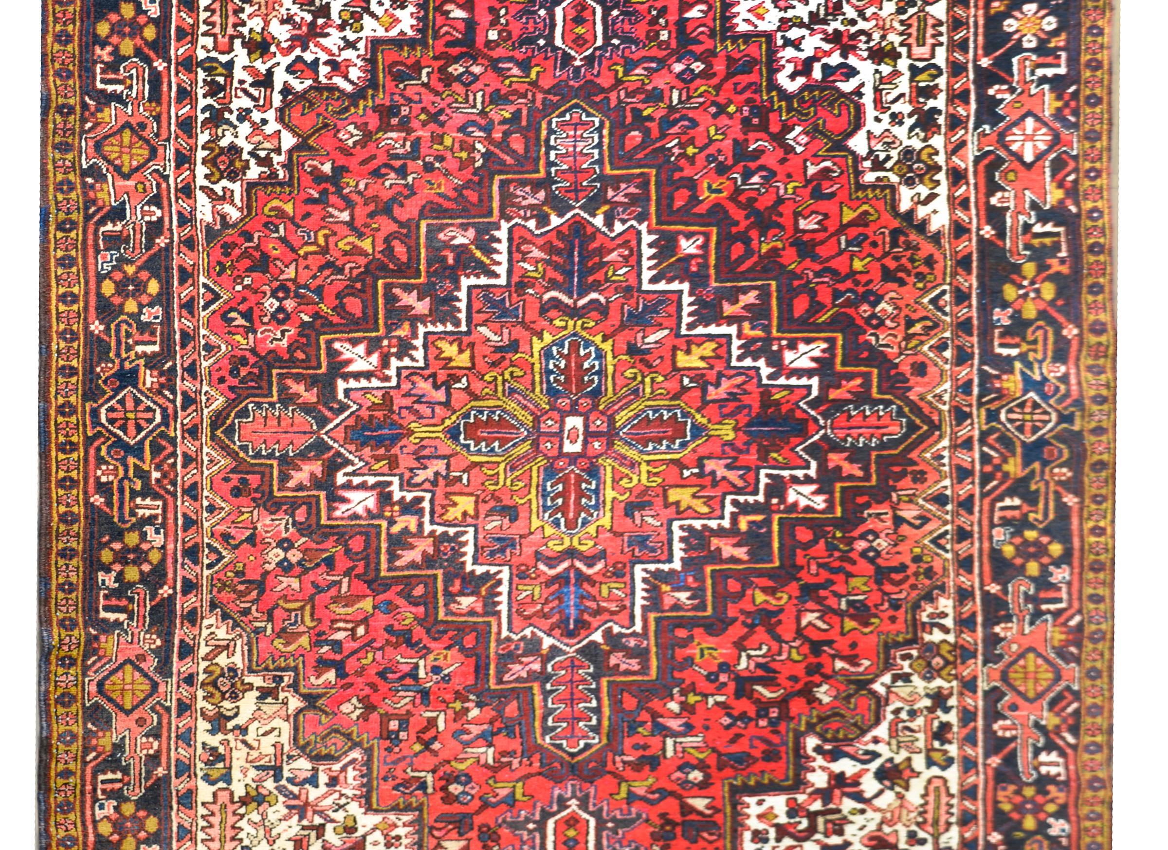A wonderful vintage Persian hertz rug with a traditional floral patterned medallion against a floral and scrolling vine patterned field, and surrounded by a stylized floral and scrolling vine patterned border.