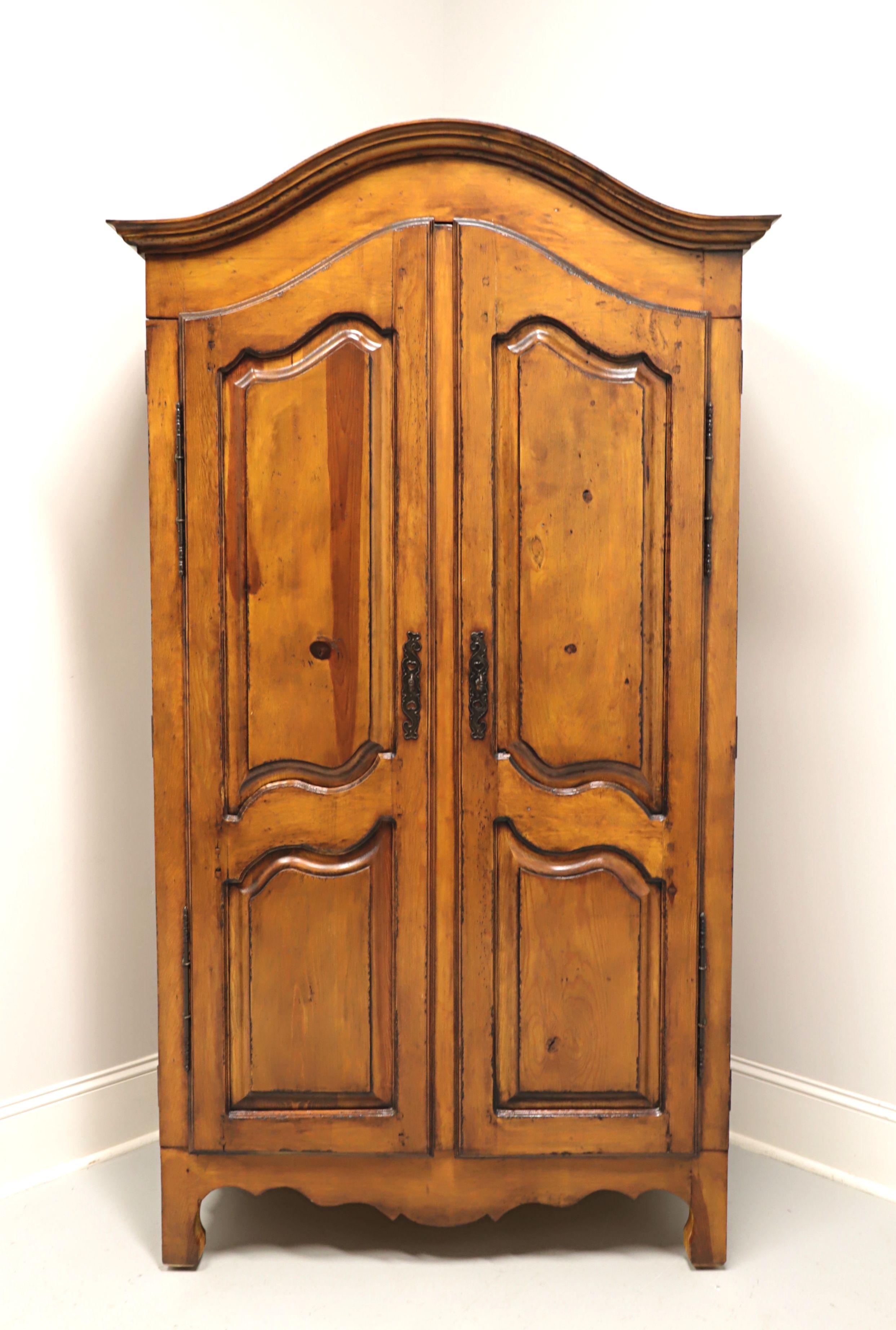A French Country style armoire / linen press, unbranded, similar quality to Drexel or Ethan Allen. Solid pine with brass hardware. Features arched top with crown molding, double raised panel fold flat doors with carved detail, carved apron and