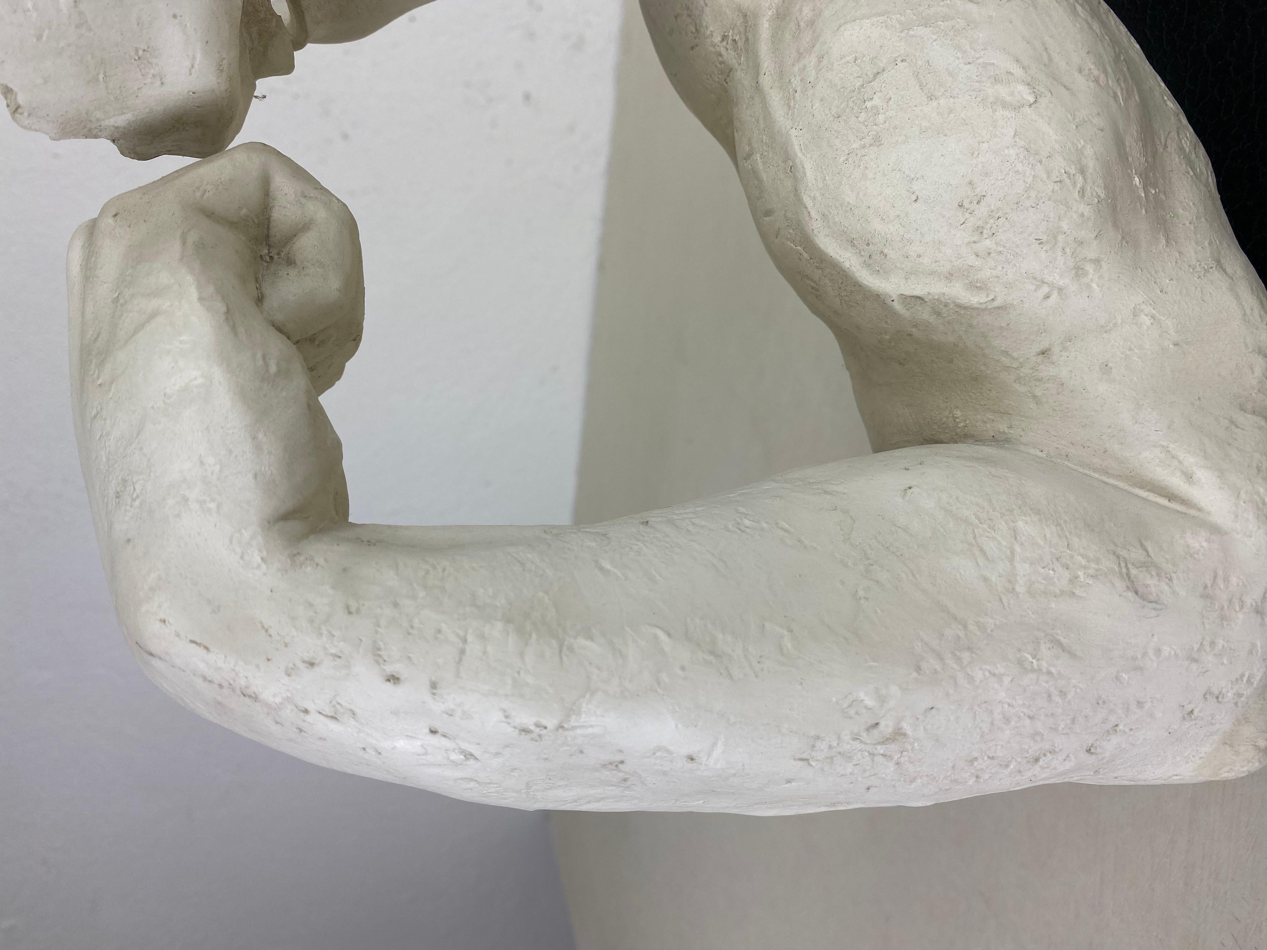 This is a late 20th century plaster male figure sculpture of a male. The sculpture rests on a black plinth. The sculpture was made in America circa 1980.