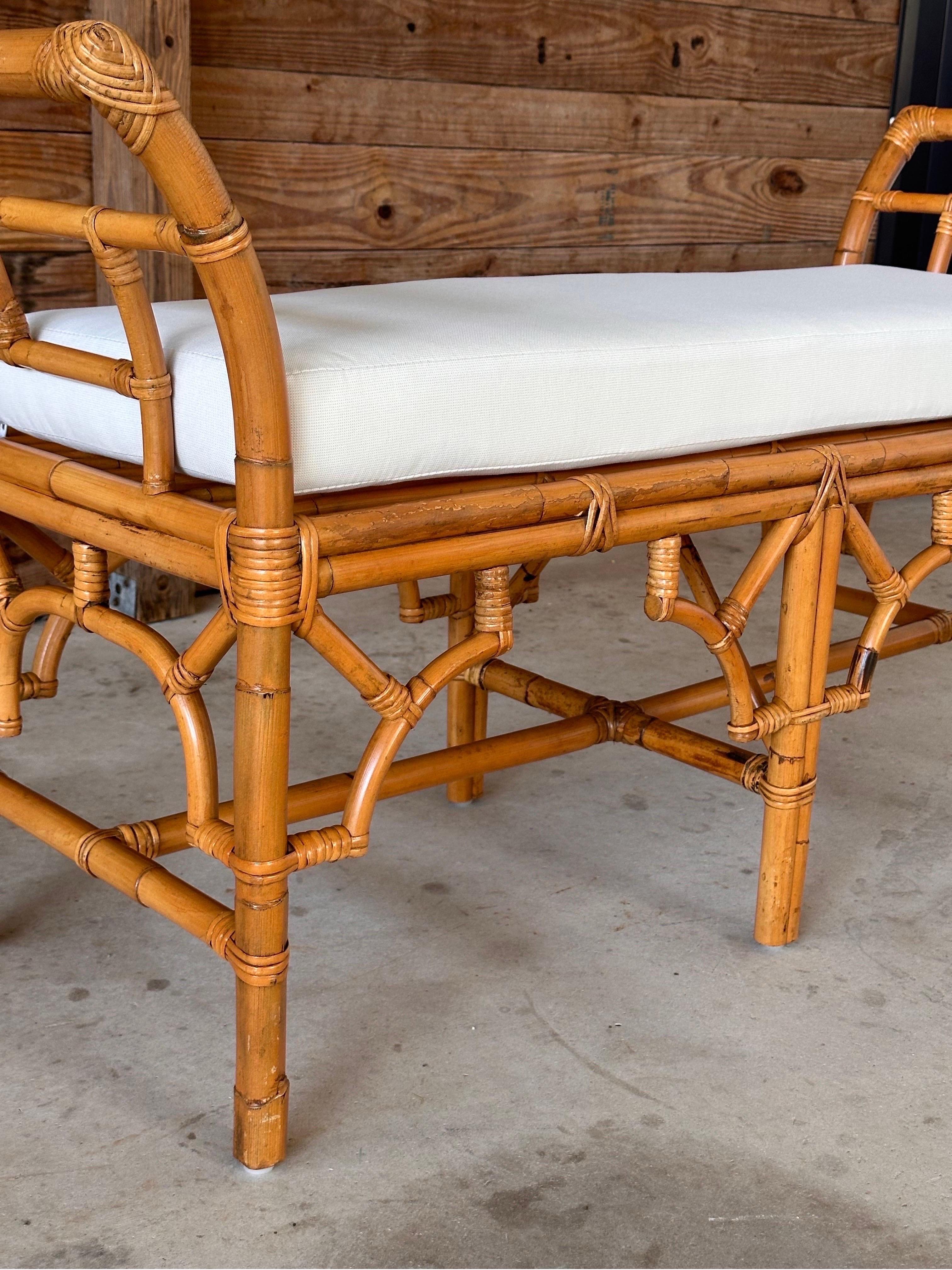 Enhance your home with this beautifully refinished rattan fretwork bench, featuring a new custom cushion upholstered in durable and stylish Sunbrella fabric.
The intricate fretwork design of the rattan frame exudes a timeless elegance, while the