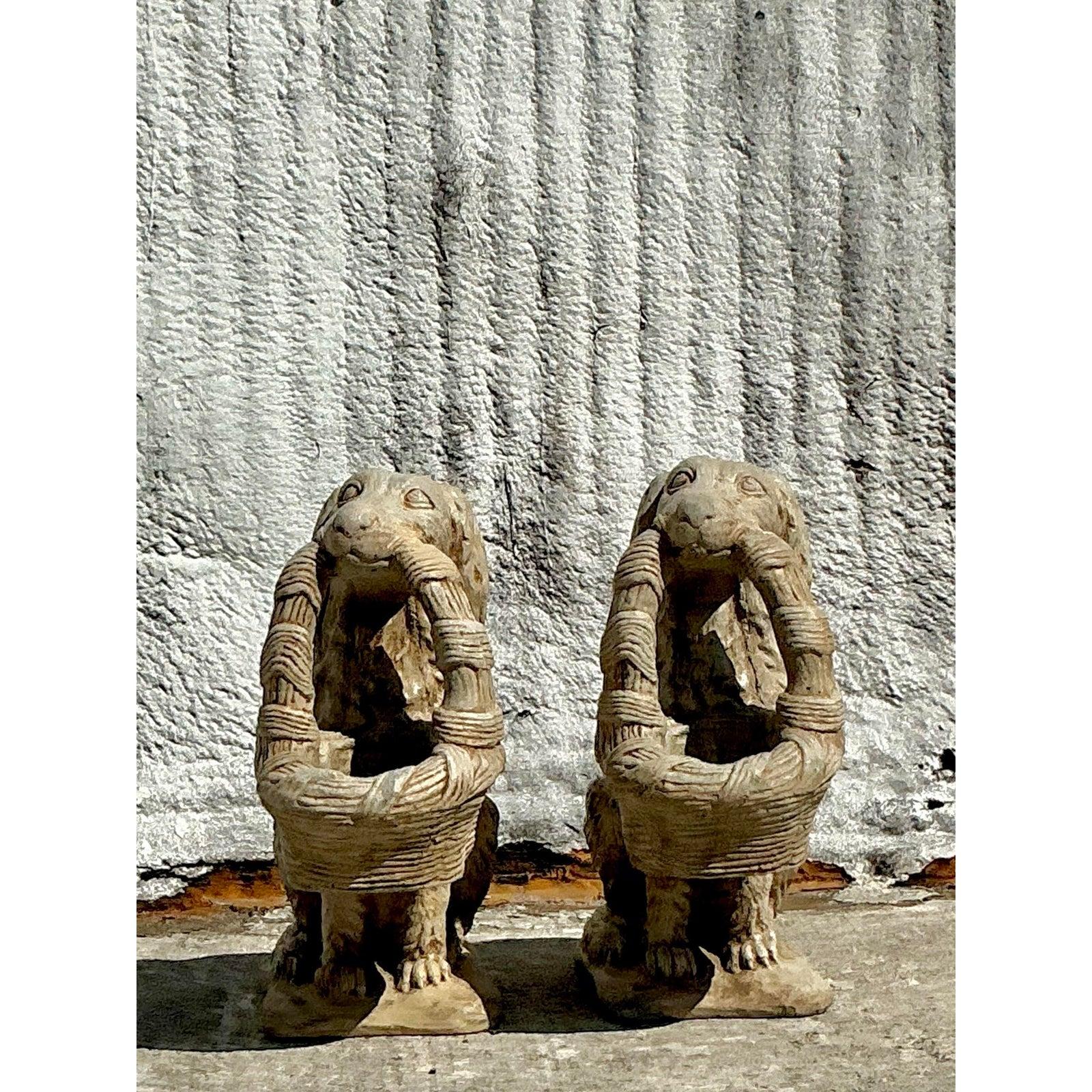 Enhance your outdoor or indoor space with this charming pair of vintage cast stone dog statues. These finely sculpted spaniels exude timeless elegance, each holding a woven basket in its mouth, adding a touch of classical sophistication. The