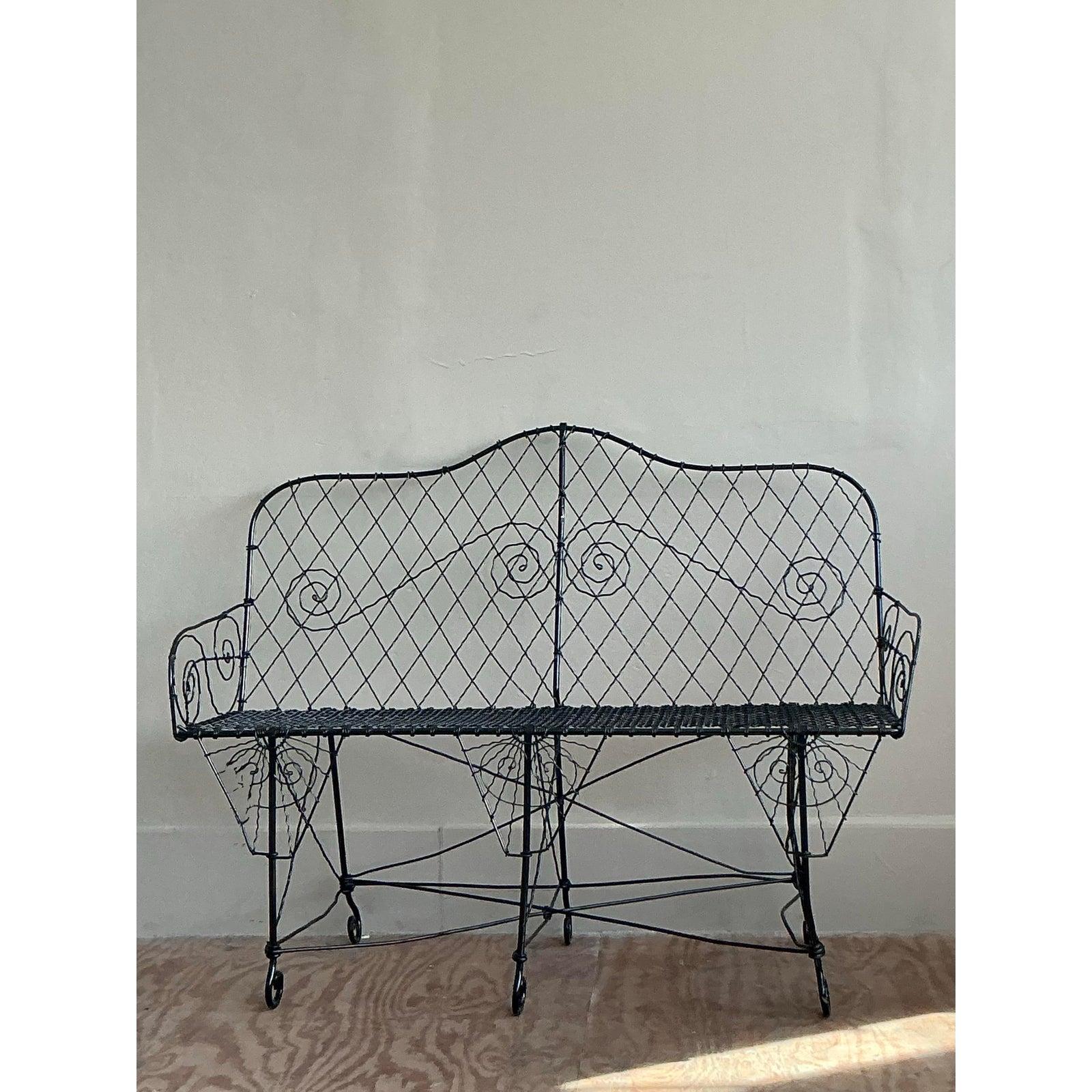 Exemple exquis de travail du fil de fer à l'ancienne, ce charmant banc capture l'esprit romantique d'un jardin à la française. Méticuleusement fabriqué à la main en fer forgé, son design incroyablement aérien et complexe témoigne d'un savoir-faire