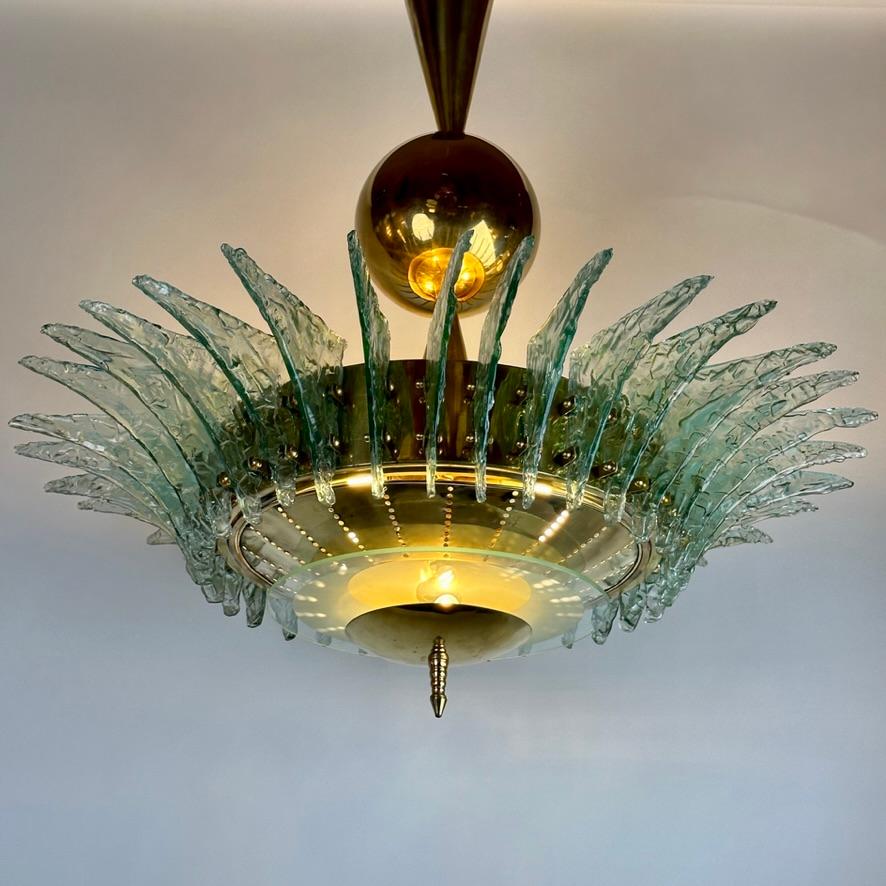 4 E14 light bulbs inside directed toward the ceiling + 2 E14 Mignon LB spreading light horizontally at the bottom of the chandelier (underneath the round frosted glass disk).
This stunning and unusual piece with textured triangular Murano glasses is