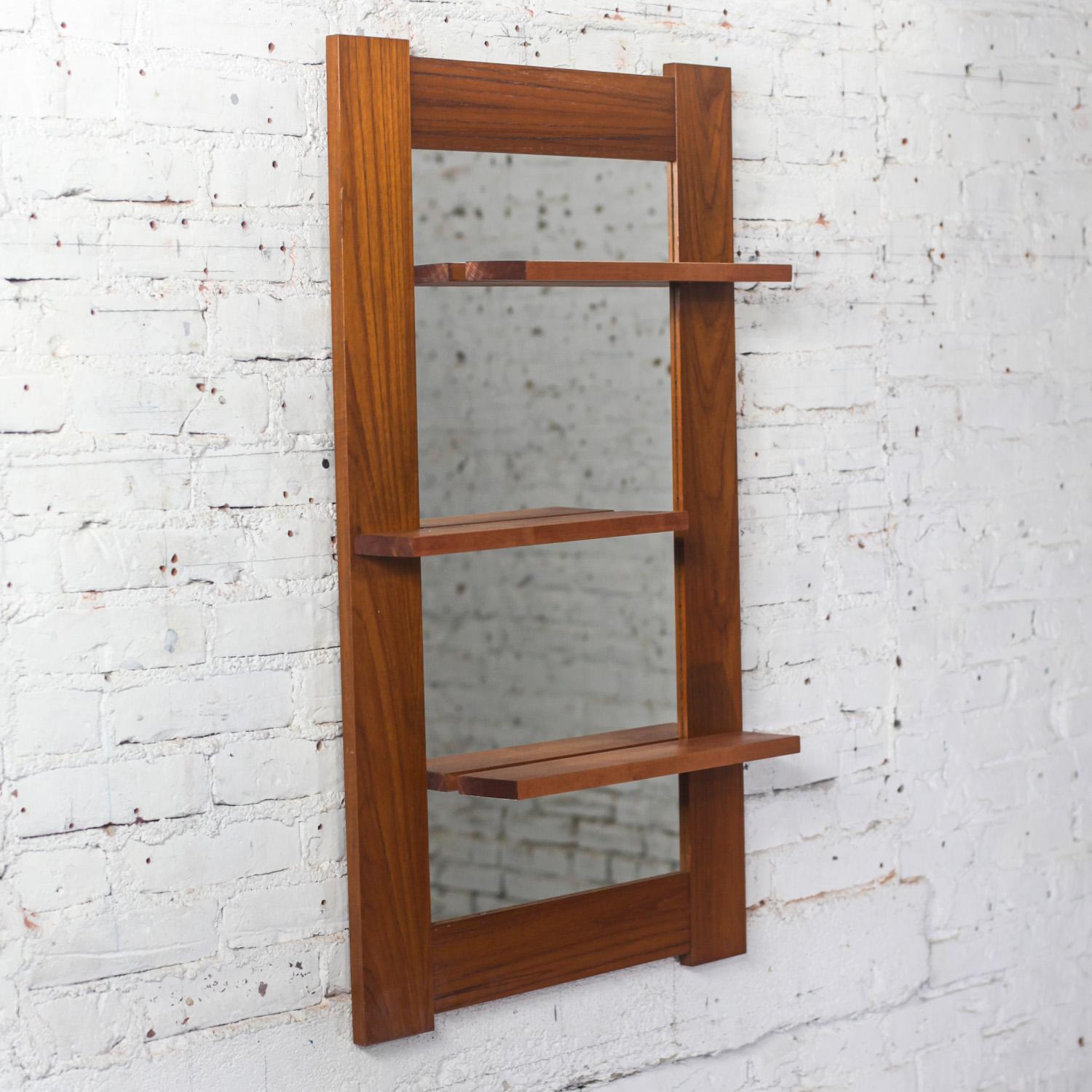 Unique Late-20th Century Scandinavian Modern teak rectangular wall mirror with display shelves. Beautiful condition, keeping in mind that this is vintage and not new so will have signs of use and wear even if it has been refinished or restored.